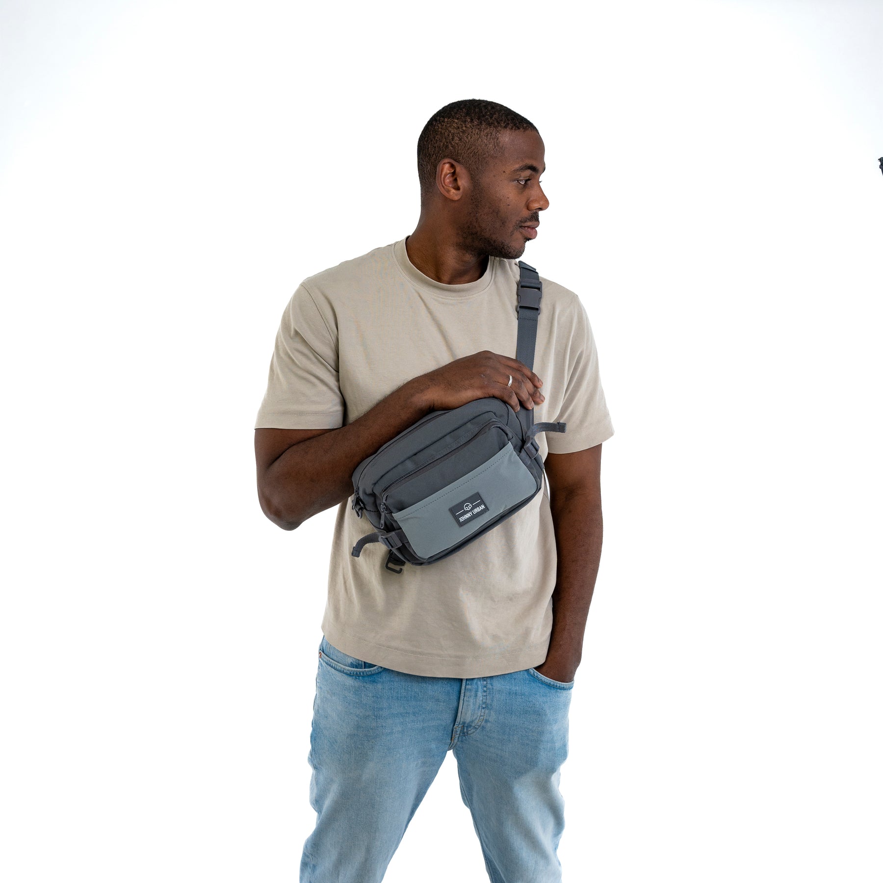 Mann trägt graue Johnny Urban Bauchtasche 'Travis' quer vor der Brust mit hellbeigem T-Shirt und Jeans