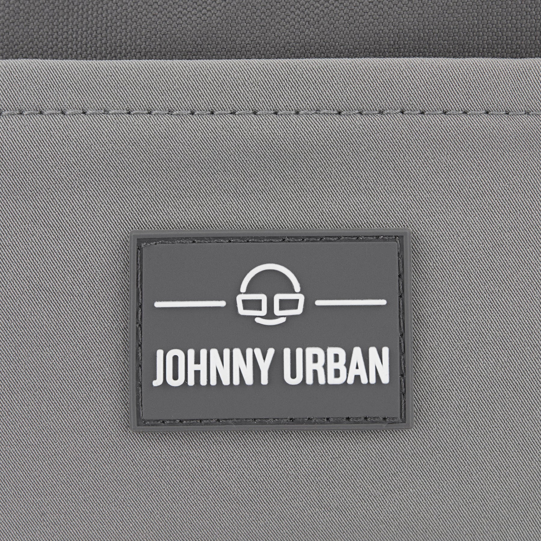 Graues Logo mit dem Text 'Johnny Urban' auf der nachhaltigen Bauchtasche 'Travis'