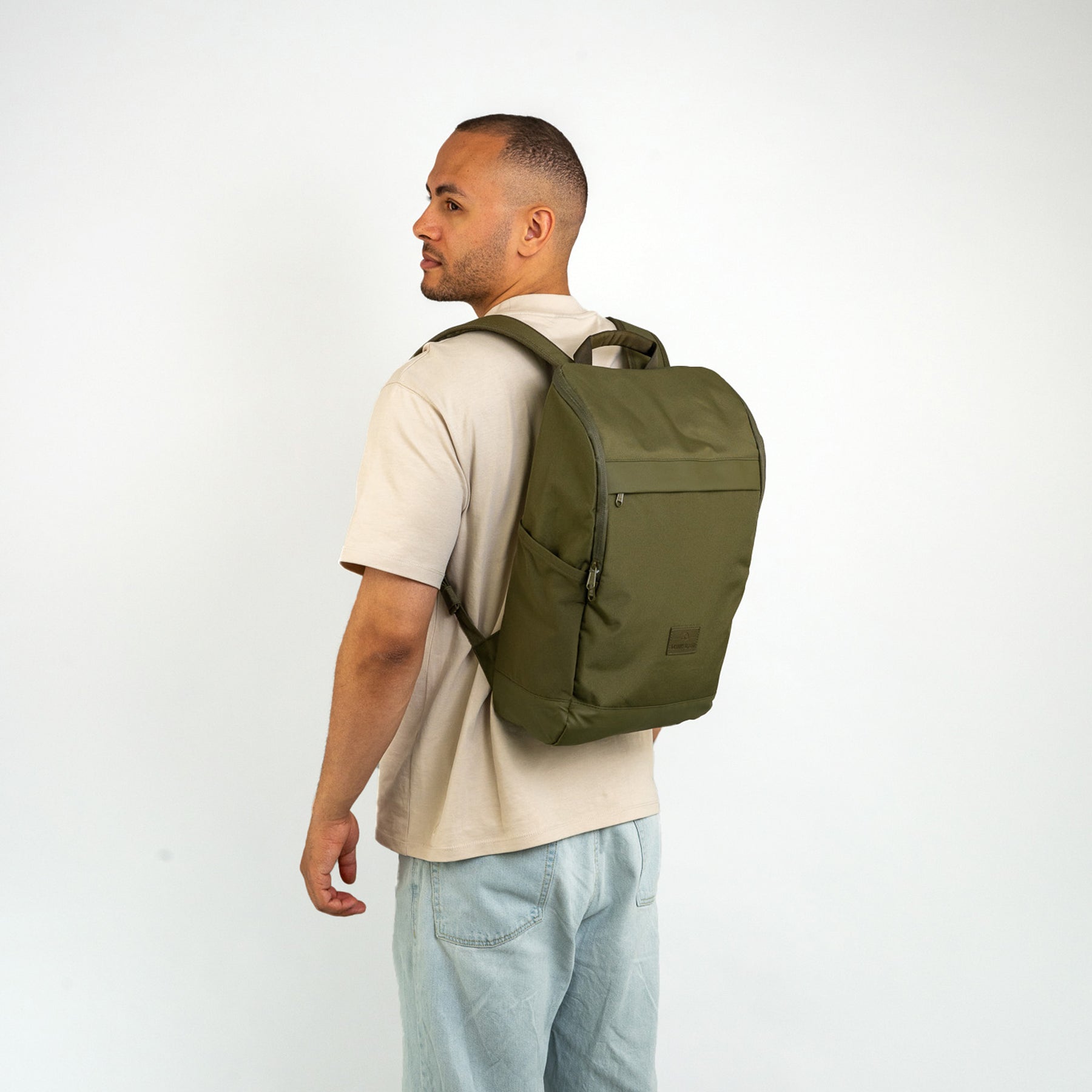 Mann trägt olivegrünen Business-Rucksack 'Jasper' von Johnny Urban über hellbeigem T-Shirt und hellblauen Jeans
