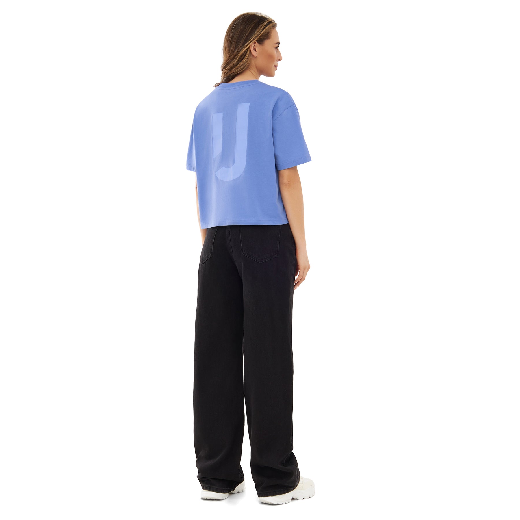 Rückansicht einer Frau mit blauer Cropped T-Shirt 'Zoey JU' und schwarzen weiten Hosen