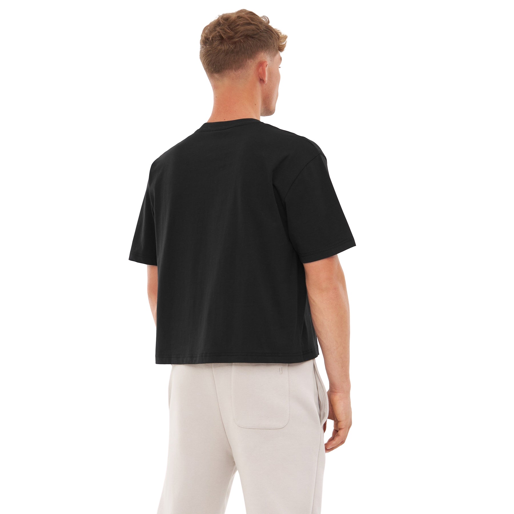 Mann von hinten trägt schwarzes Oversize Cropped T-Shirt 'Zoey' und helle Hose