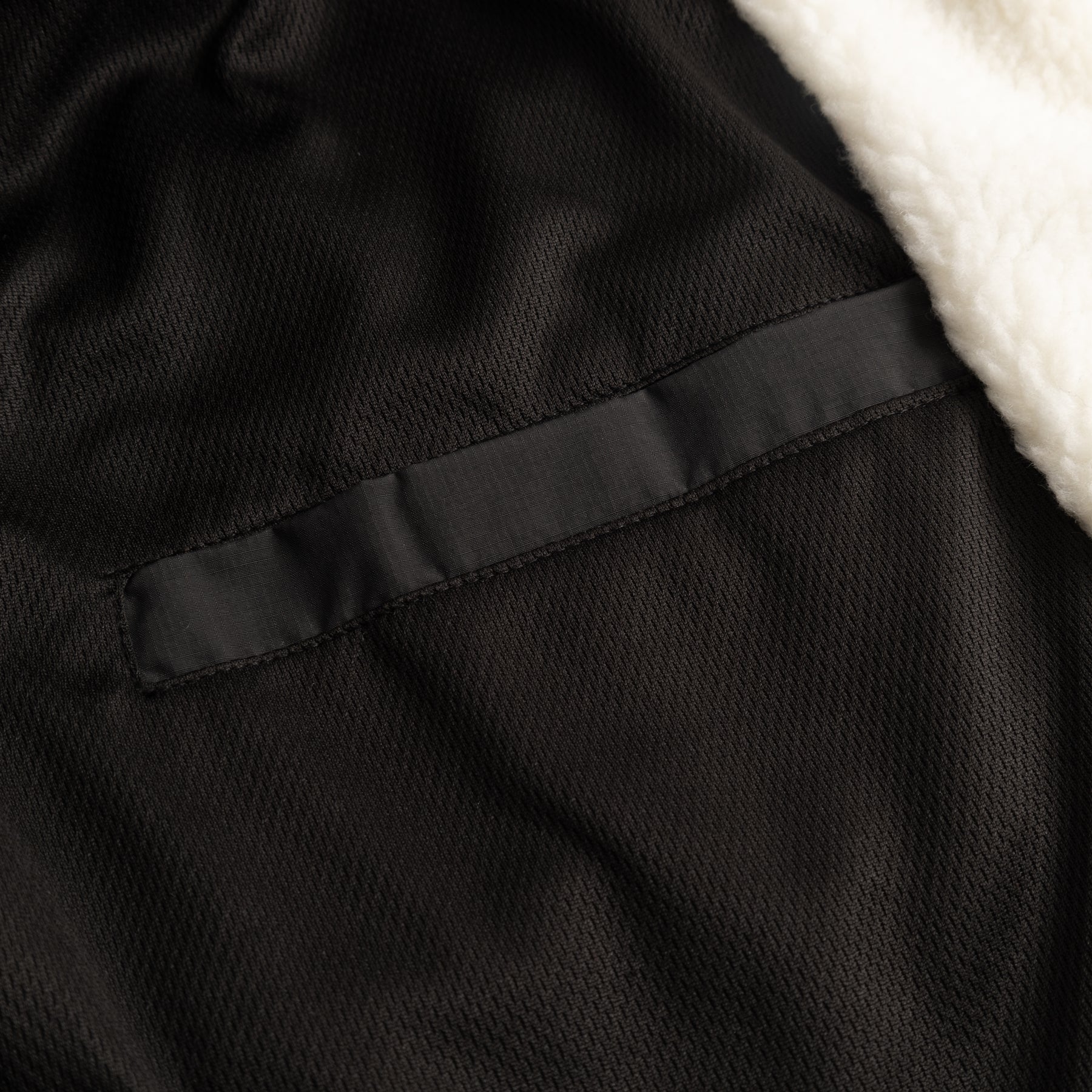 Innenseite der Cropped Teddy Fleecejacke ‚Carey‘ mit schwarzem Textilfutter und weißem Teddyfellrand