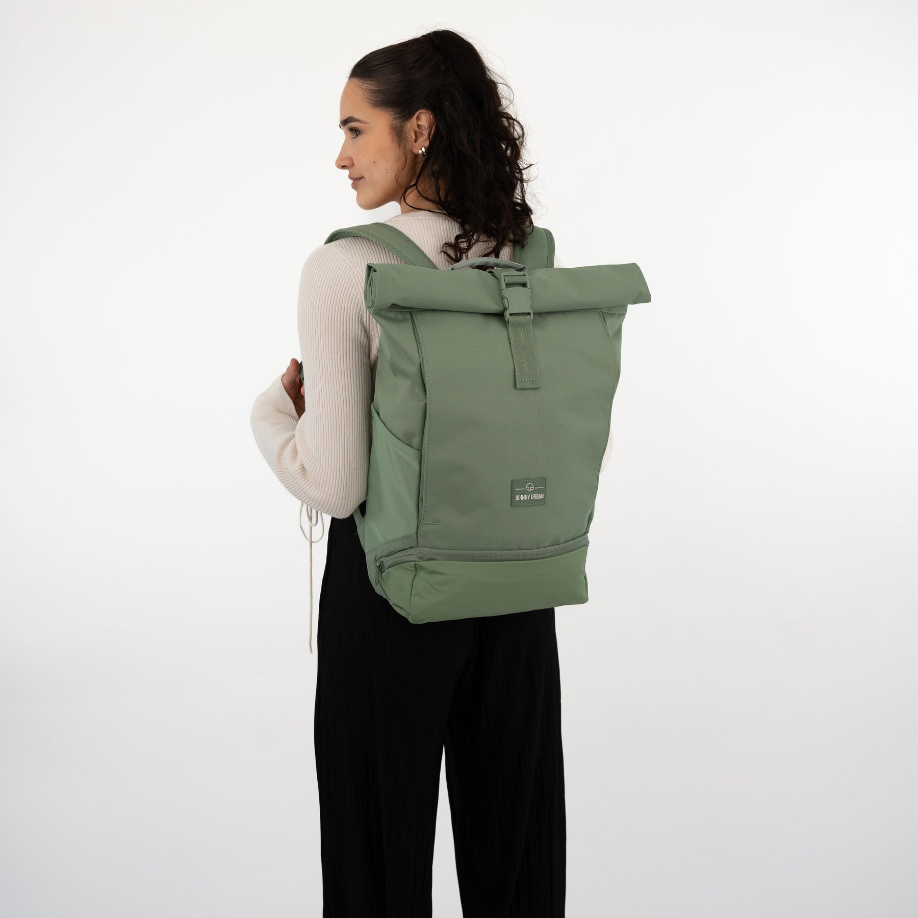 Frau trägt grünen Rolltop Rucksack ‚Allen Medium‘ von Johnny Urban, seitlich zu sehen
