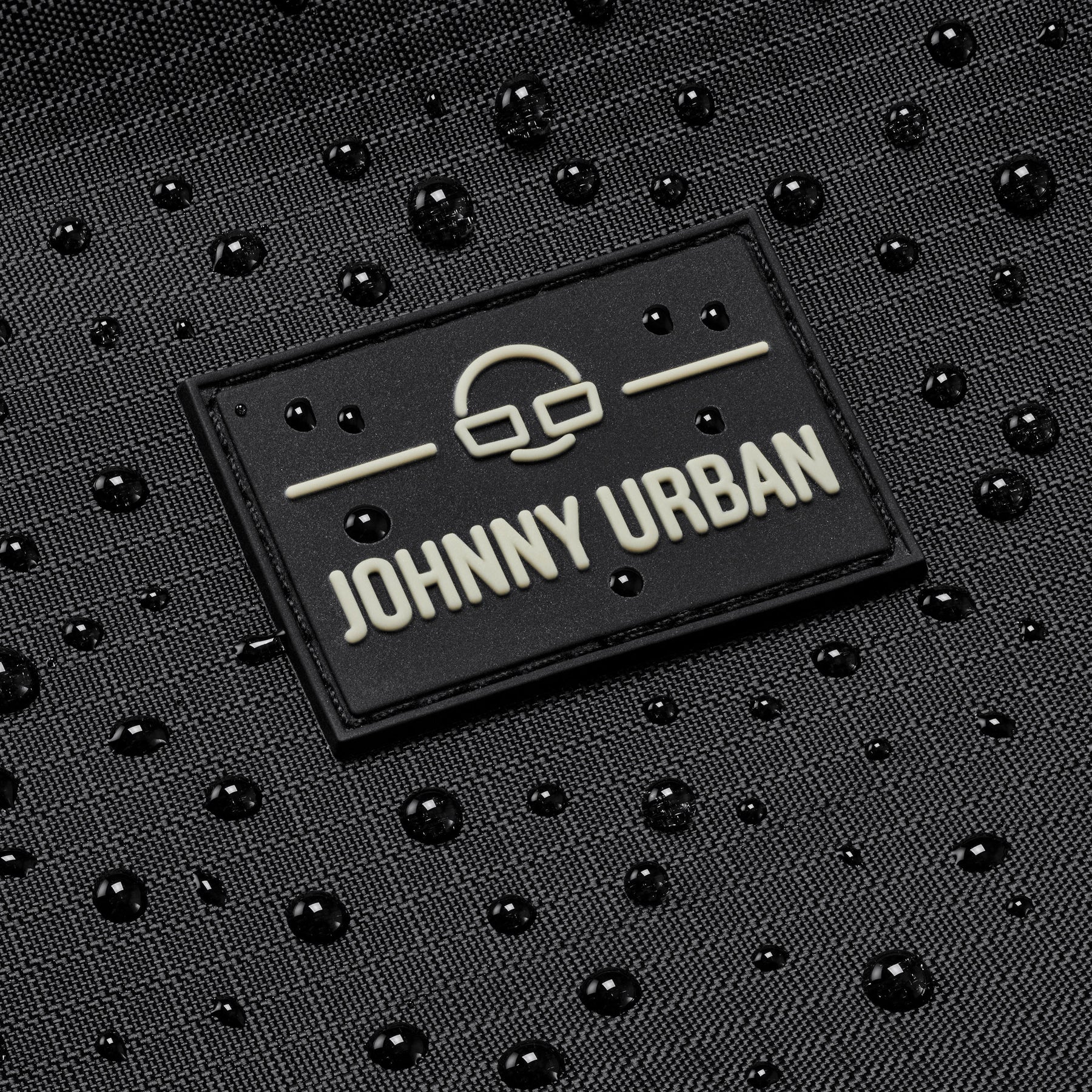 Schwarzes, wasserabweisendes Material mit Johnny Urban Logo und Wassertröpfchen