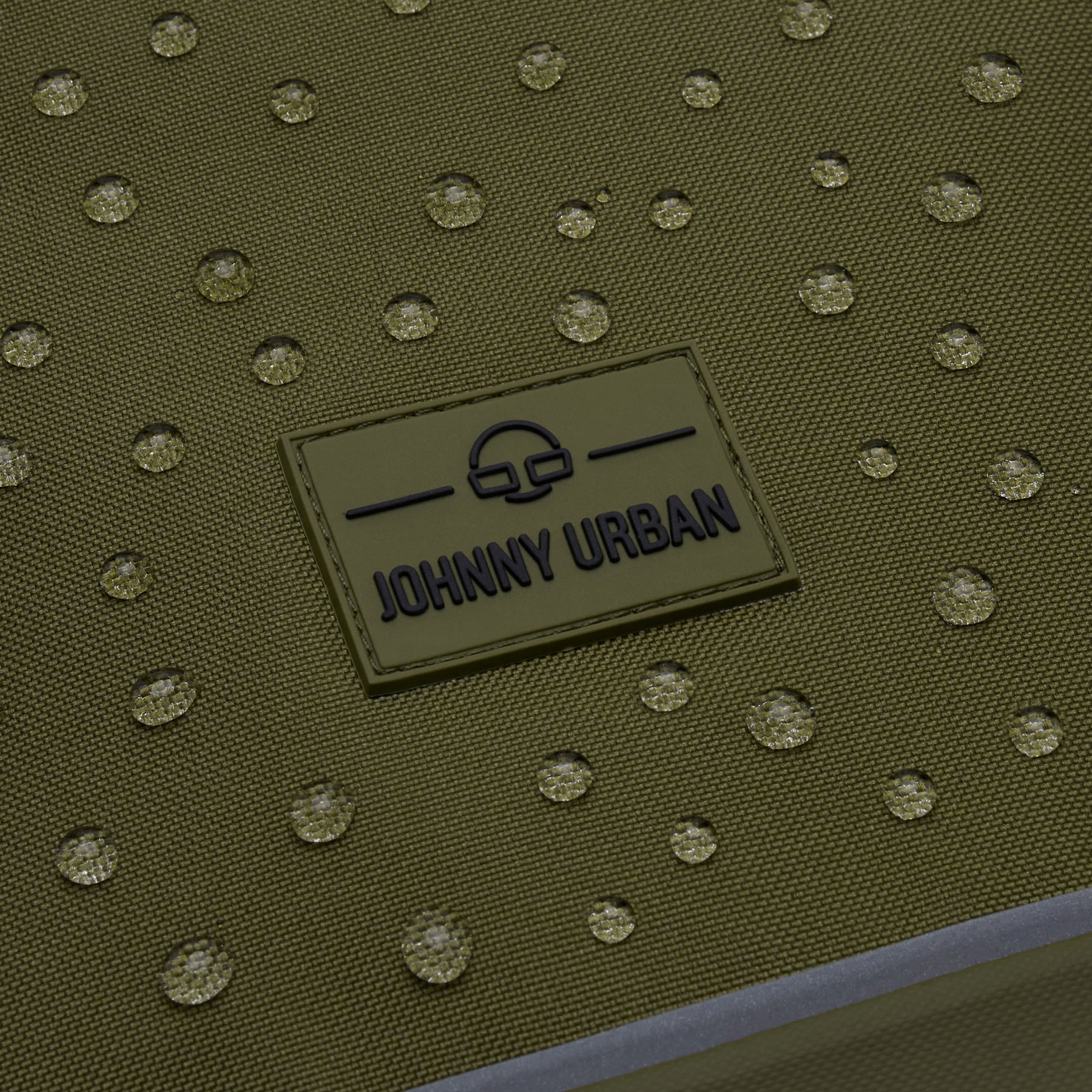 Nahe Aufnahme des wasserabweisenden olivgrünen Rolltop Rucksacks 'Robin Medium' mit Johnny Urban Markenlogo und Wassertröpfchen