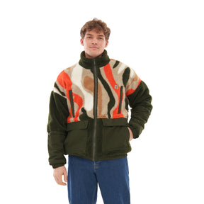 Mann trägt Teddy Fleecejacke 'Carson' mit olivgrünen, weißen, braunen und orangen Mustern und blauer Jeans