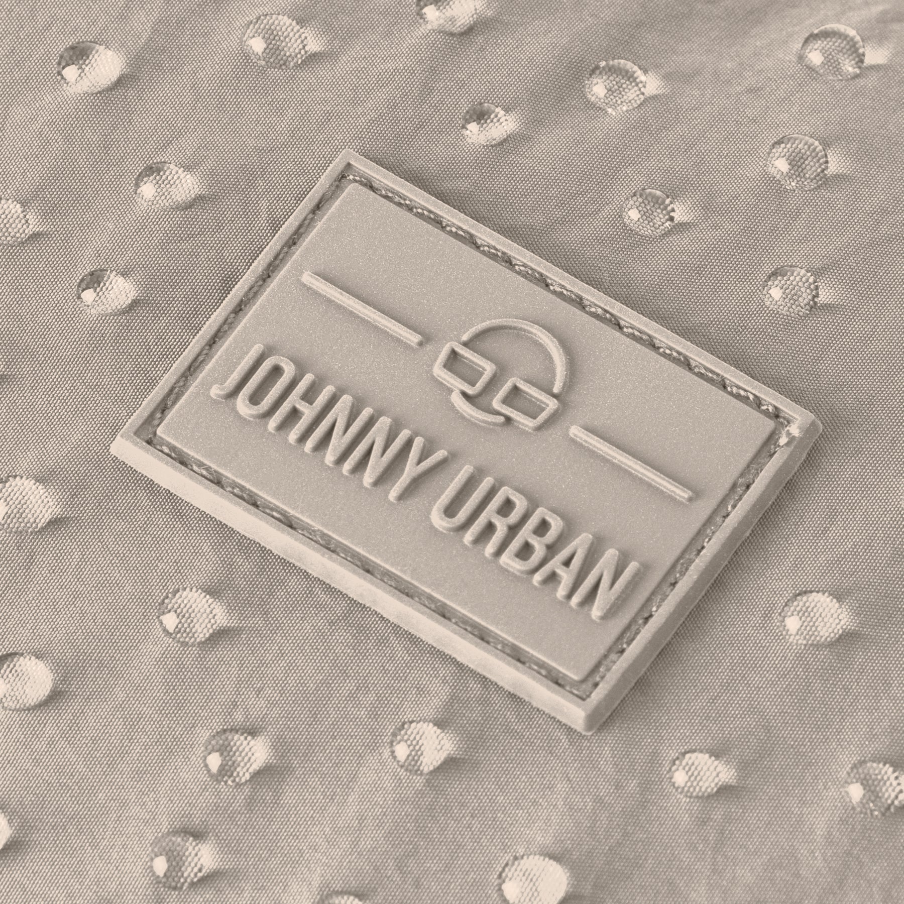 Johnny Urban Markenlabel auf wasserabweisendem beige Stoff mit Wassertropfen