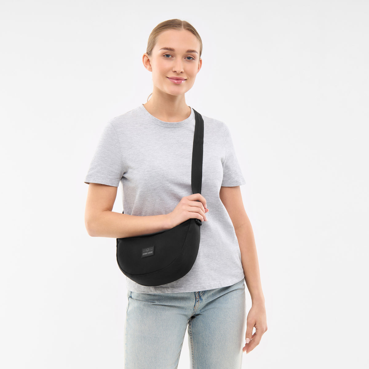 Dame trägt schwarze Half Moon Bag 'Ally Small' von Johnny Urban mit grauem T-Shirt und Jeans