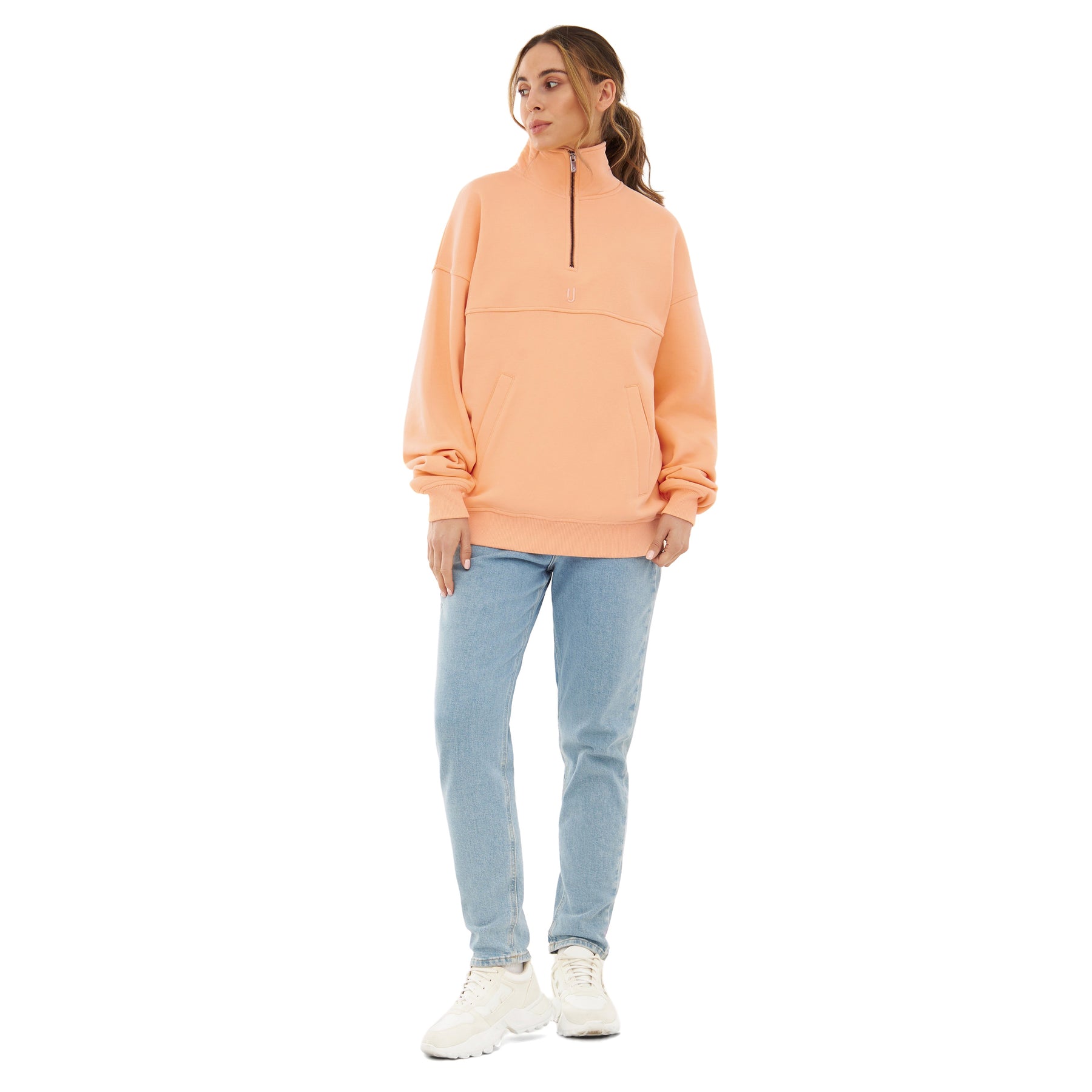 Frau trägt Peach-farbenen Half Zip Sweatshirt 'Cooper' von Johnny Urban mit hellblauen Jeans und weißen Schuhen