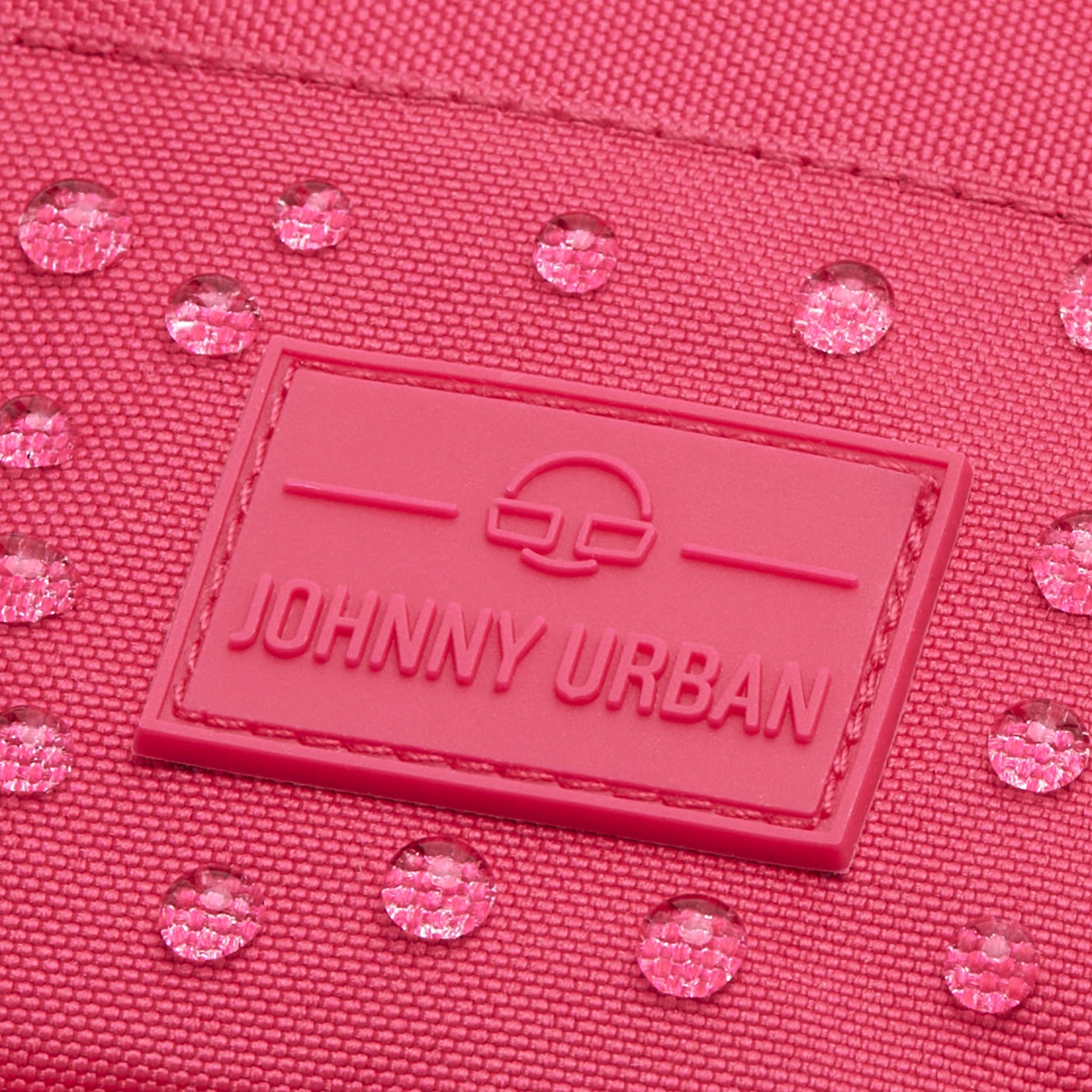 Nahaufnahme der wasserabweisenden pinkfarbenen Umhängetasche 'Josh' von Johnny Urban mit sichtbaren Wassertropfen und Markenlogo
