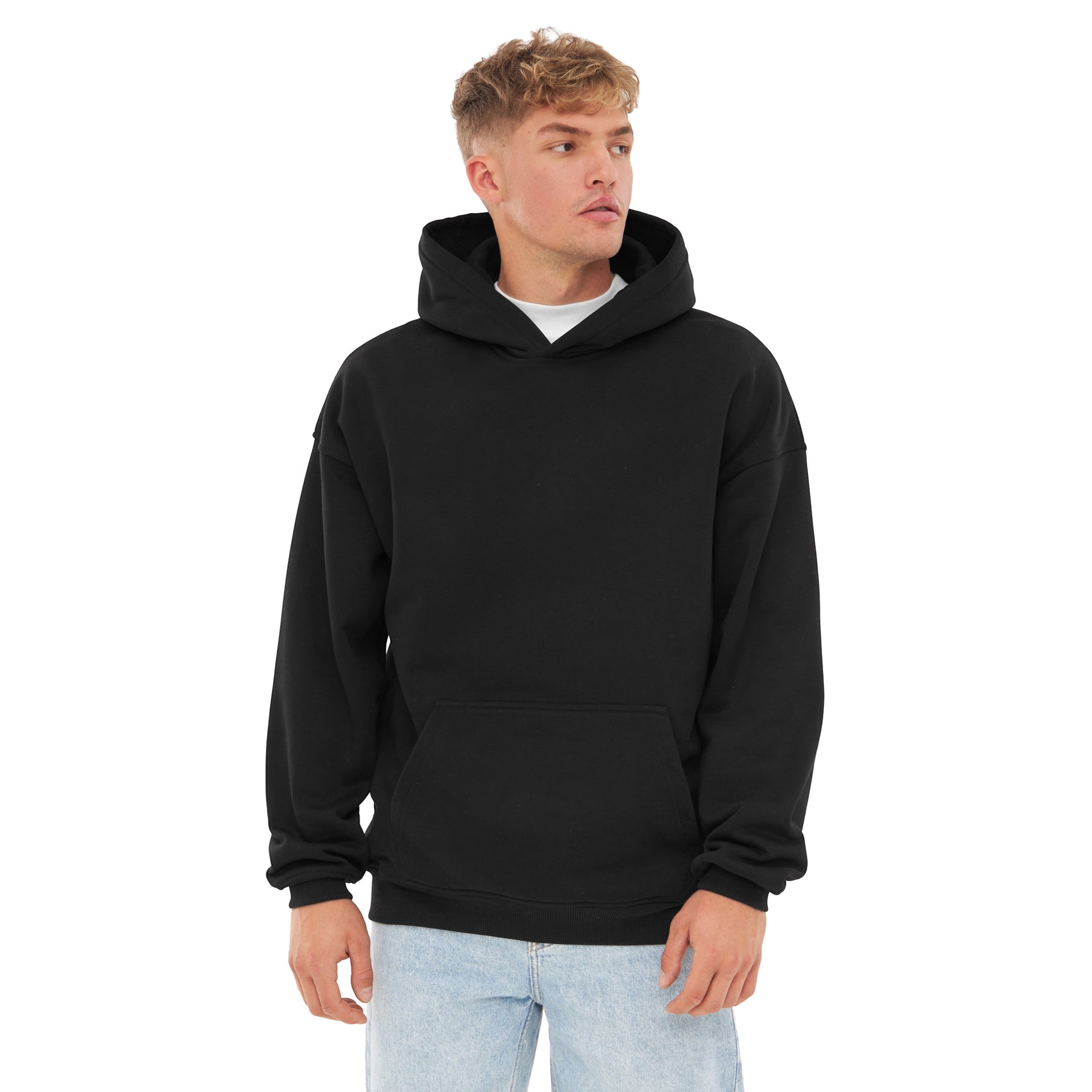 Mann trägt schwarzen oversized Hoodie 'Cody' mit Kängurutasche und Kapuze, kombiniert mit hellblauen Jeans