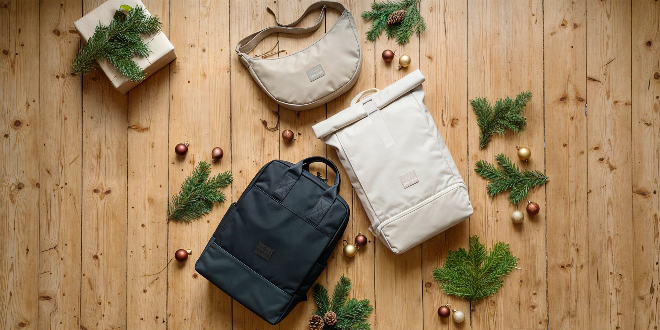 Johnny Urban Taschen und Rucksäcke auf einem Laminatboden mit Tannenzweigen und Weihnachtsdeko.