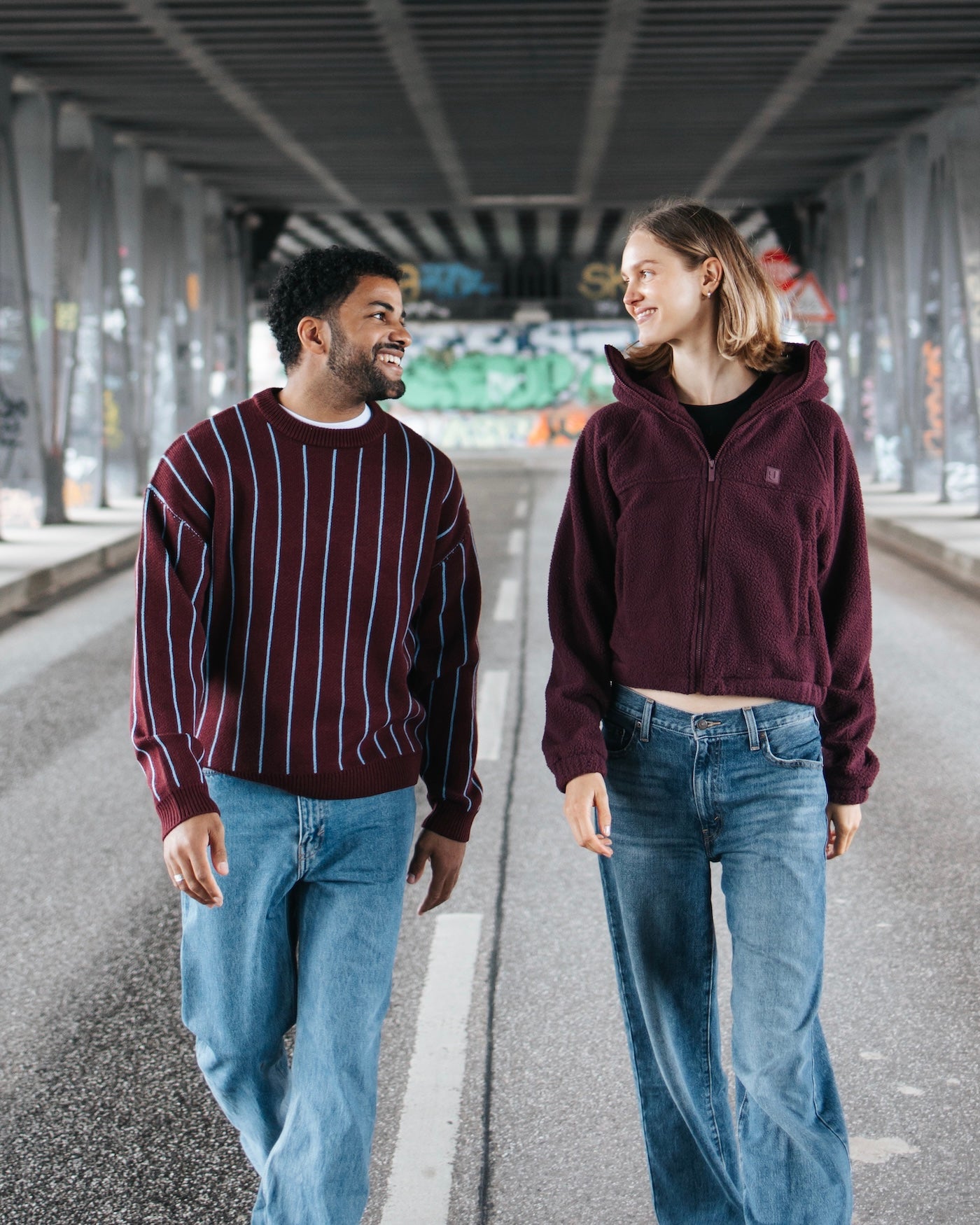 Frau und Mann in Johnny Urban-Halfzip-Fleecepullover und Wendejacke vor einem Waldhintergrund.