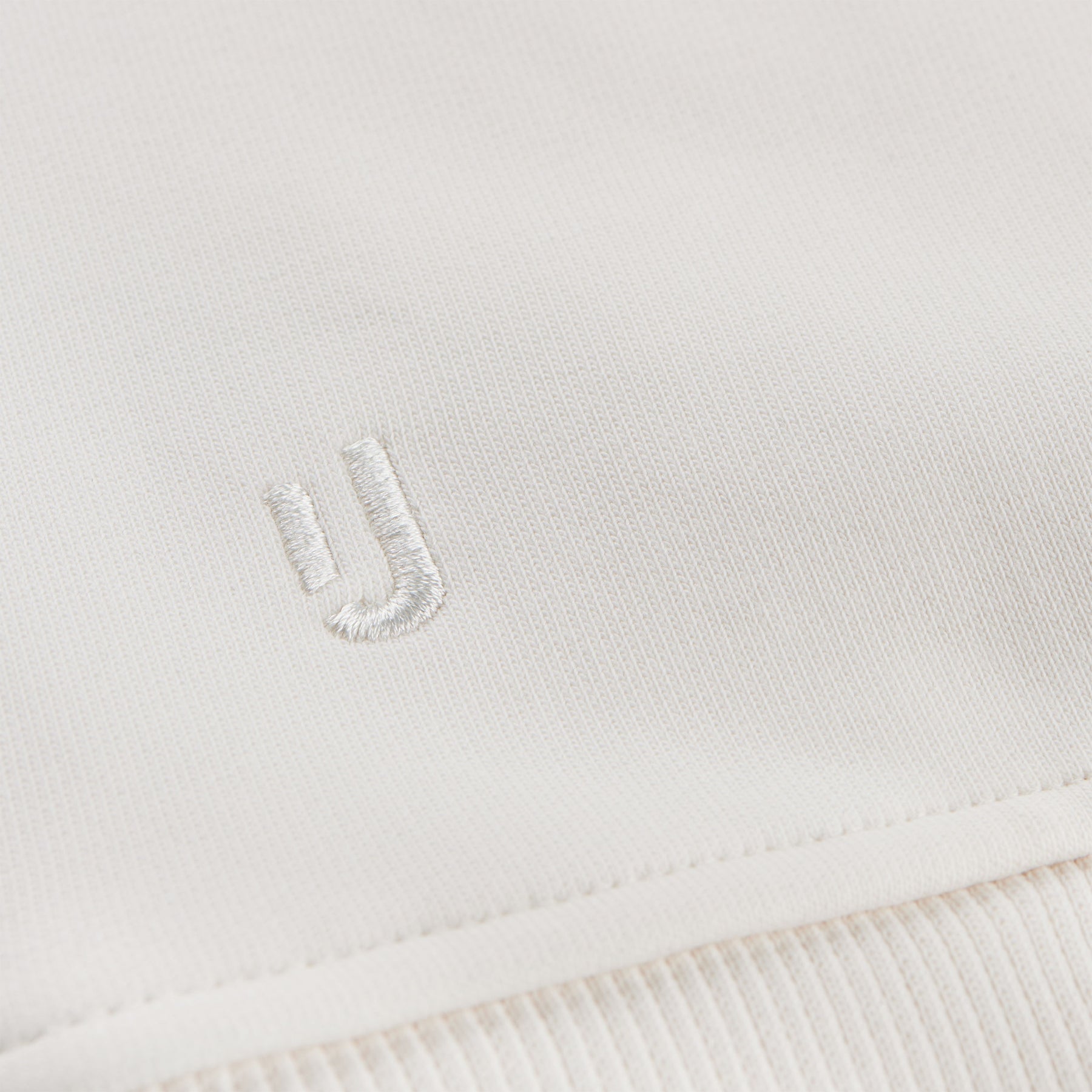 Nahe Ansicht des weißen gestickten Johnny-Urban-Logos auf cremeweißem Oversized Hoodie 'Cody'