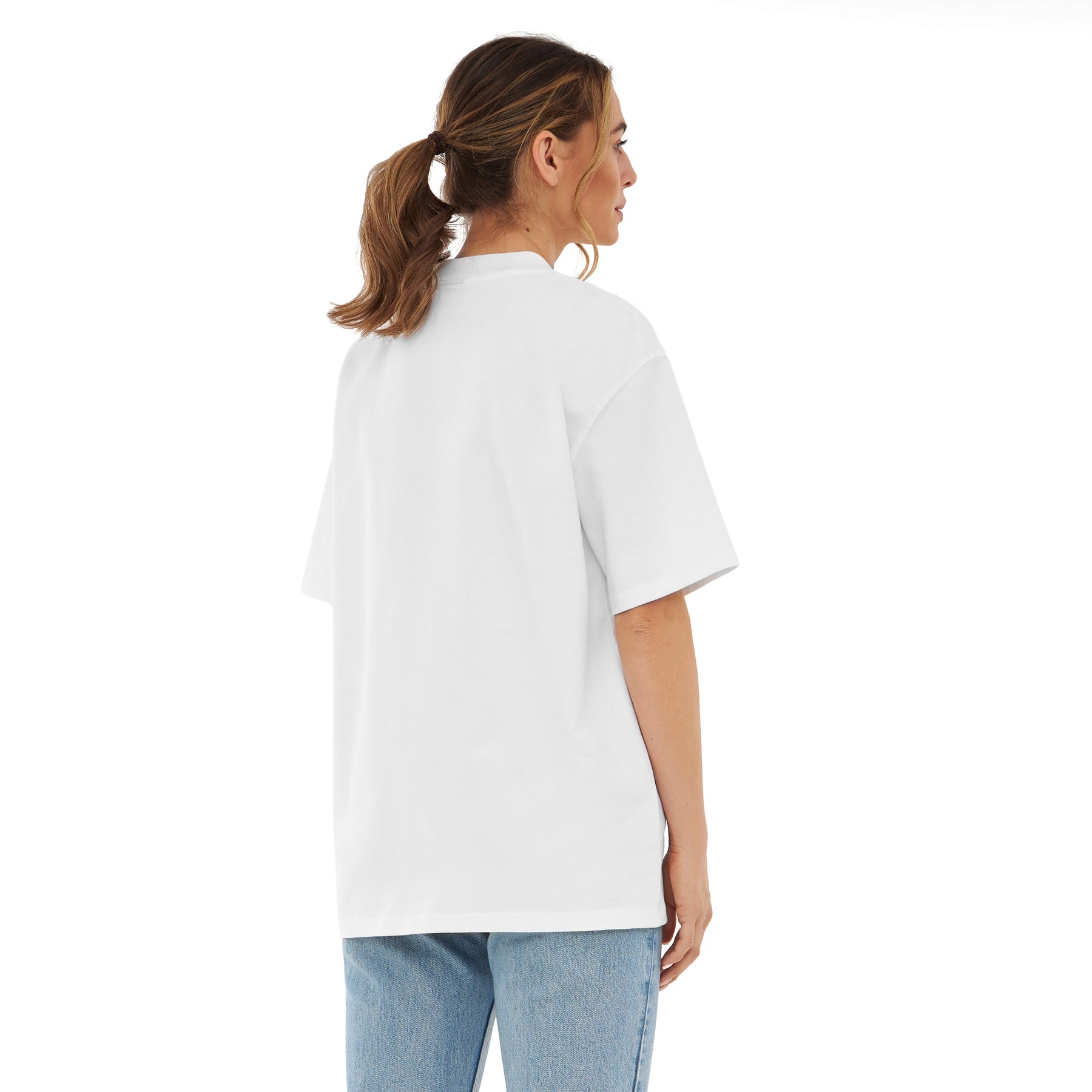 Frau trägt oversized T-Shirt 'Sammy' in Weiß, Rückansicht, mit blonden Zöpfen, dazu blaue Jeans