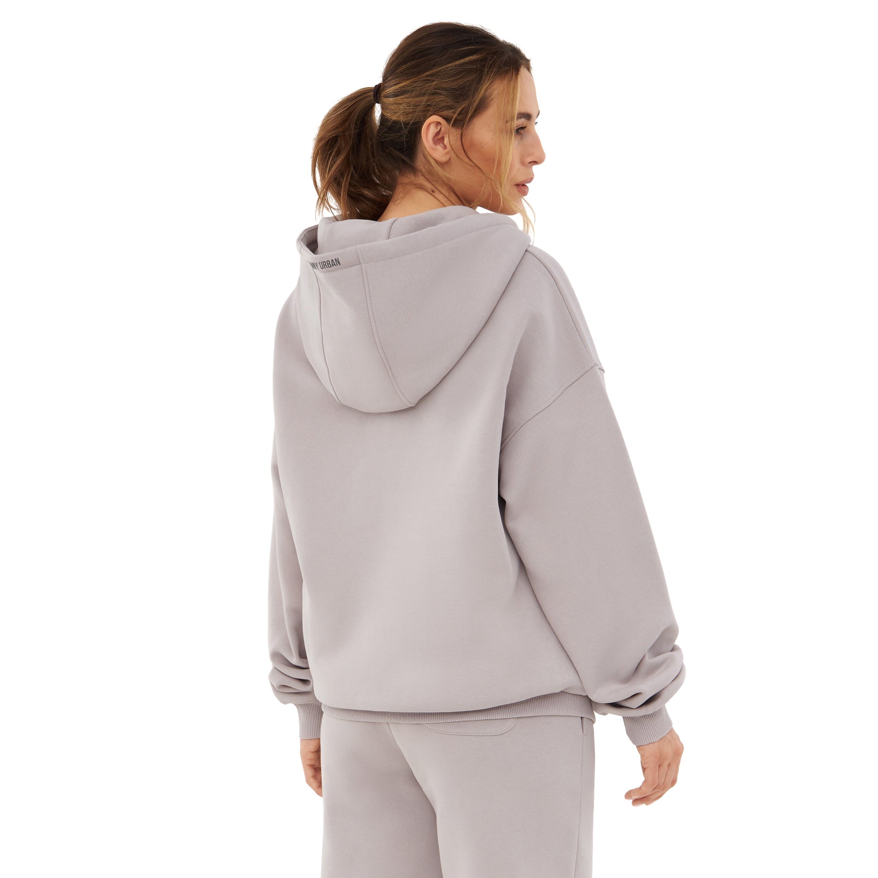 Frau von hinten in oversized Zip Hoodie 'Caleb' in graubeige mit Kapuze, entspanntem Schnitt und langen Ärmeln