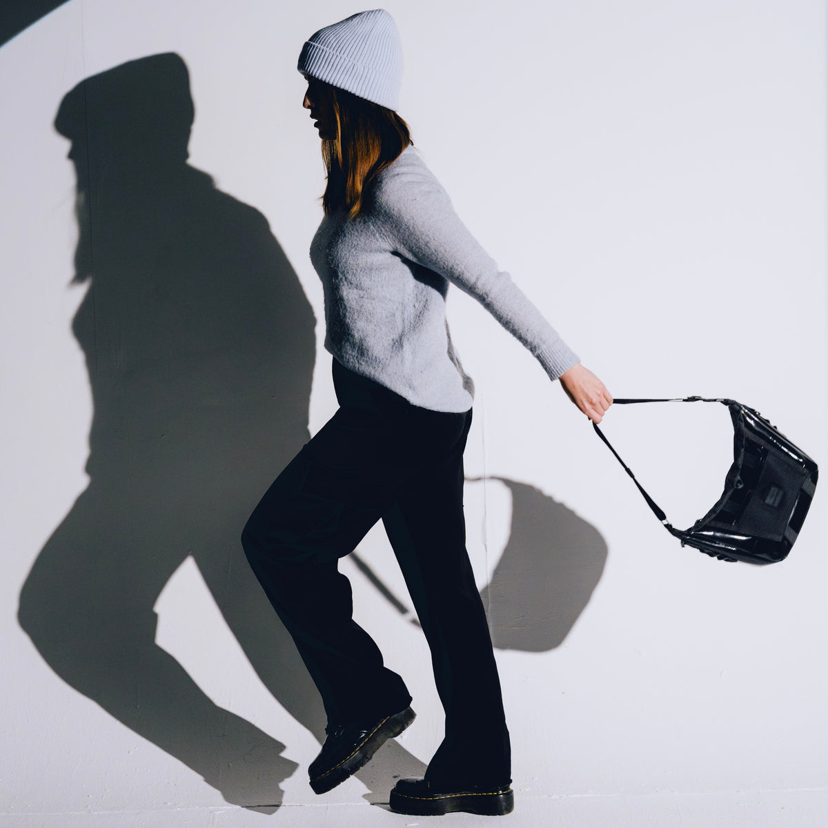 Frau mit grauem Pullover und Mütze trägt schwarze Handtasche 'Liv' von Johnny Urban