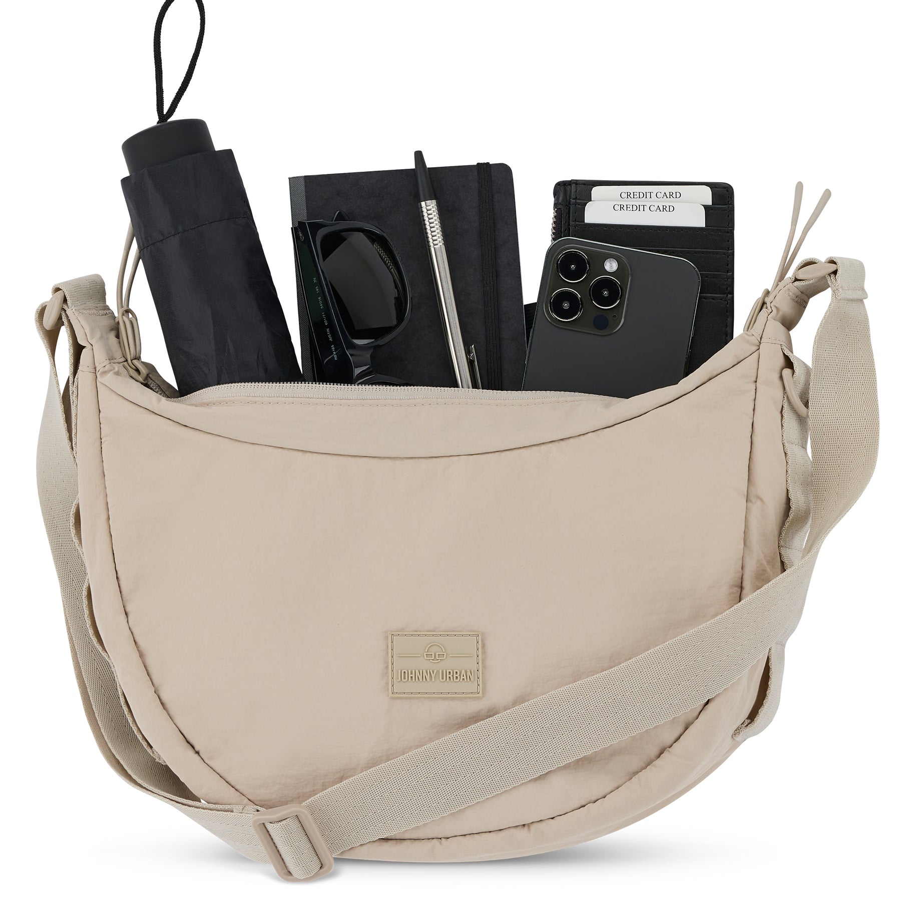 Halbmondtasche 'Kaia Medium' von Johnny Urban in Beige mit schwarzen Sonnenbrillen, Regenschirm, Notizbuch, Stift, Smartphone und Kreditkarten