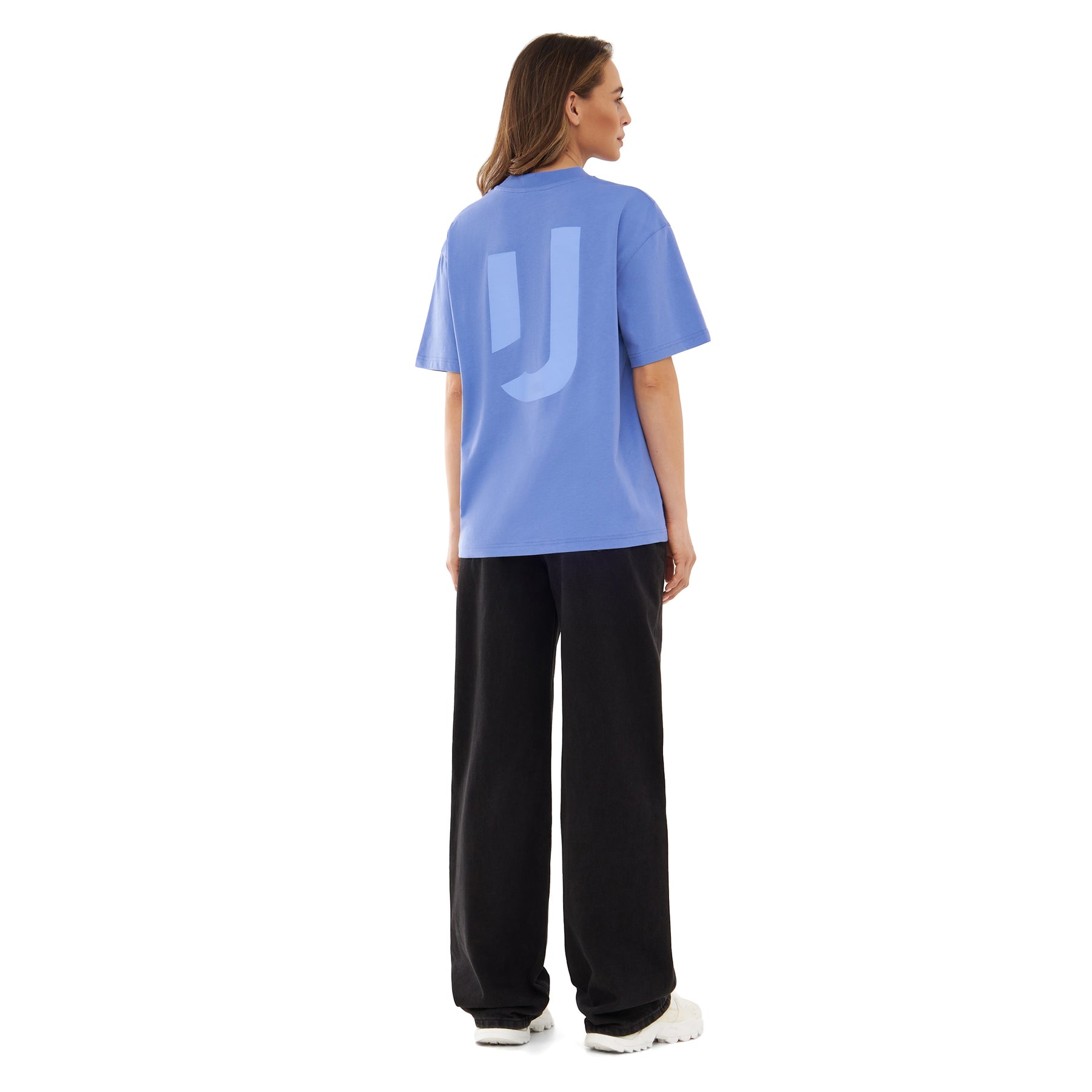 Frau trägt lila Johnny Urban Oversize-T-Shirt 'Sammy JU' mit großem J-Logo auf dem Rücken, schwarze Hose