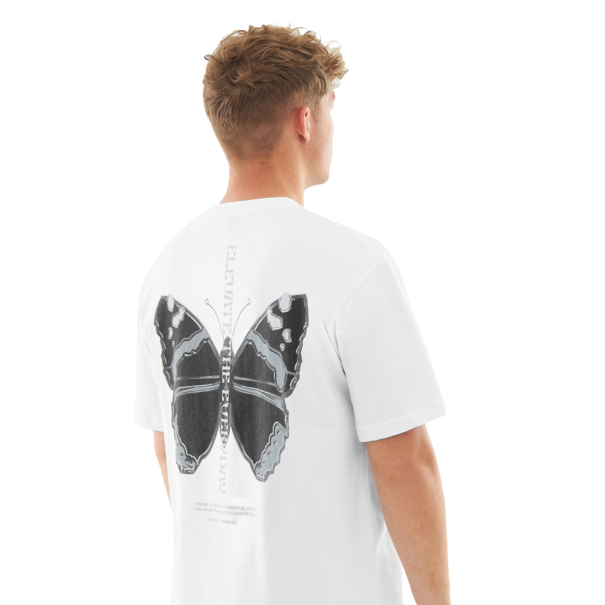 Junger Mann von hinten mit weißem Oversize-T-Shirt 'Sammy Chrome Butterfly' mit großem schwarzem Schmetterlingsdruck auf dem Rücken