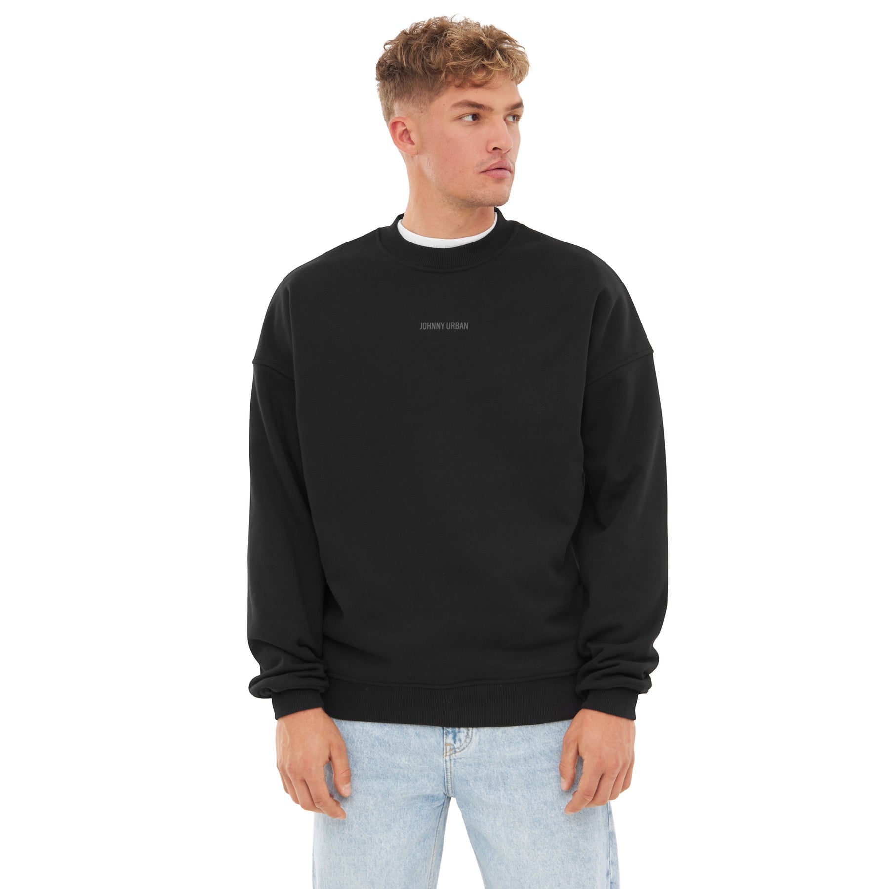 Mann trägt schwarzen oversized Crewneck 'Carter' mit kleinem Johnny Urban Print auf der Brust