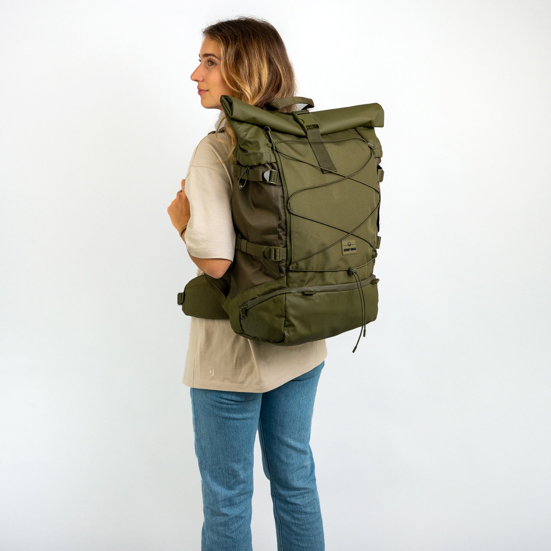 Frau trägt olivgrünen Reiserucksack 'Allen XL Travel' von Johnny Urban mit Rollverschluss und Hüftgurt