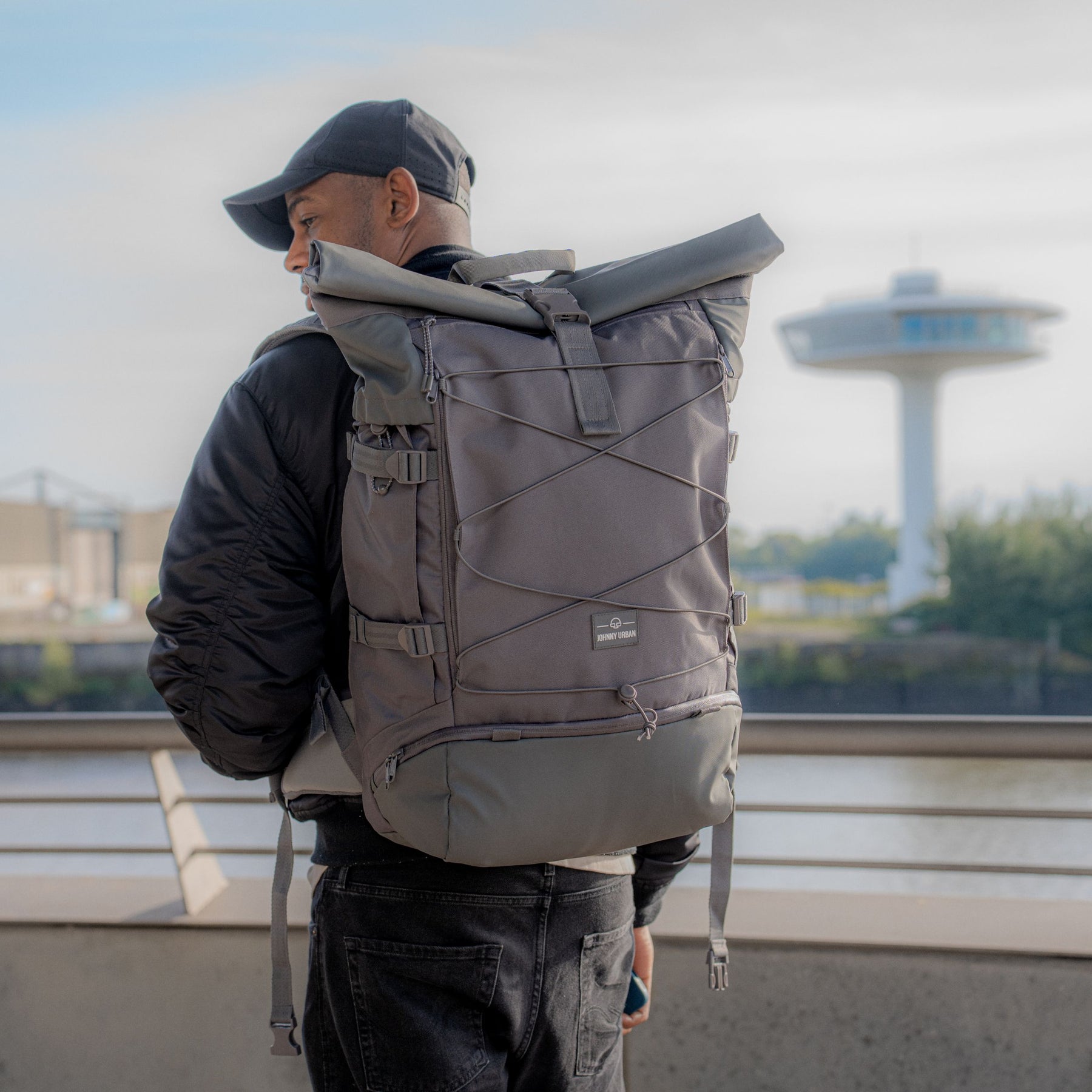 Mann trägt grauen Johnny Urban Reiserucksack 'Allen XL Travel' mit Rollverschluss und Außenspannbändern