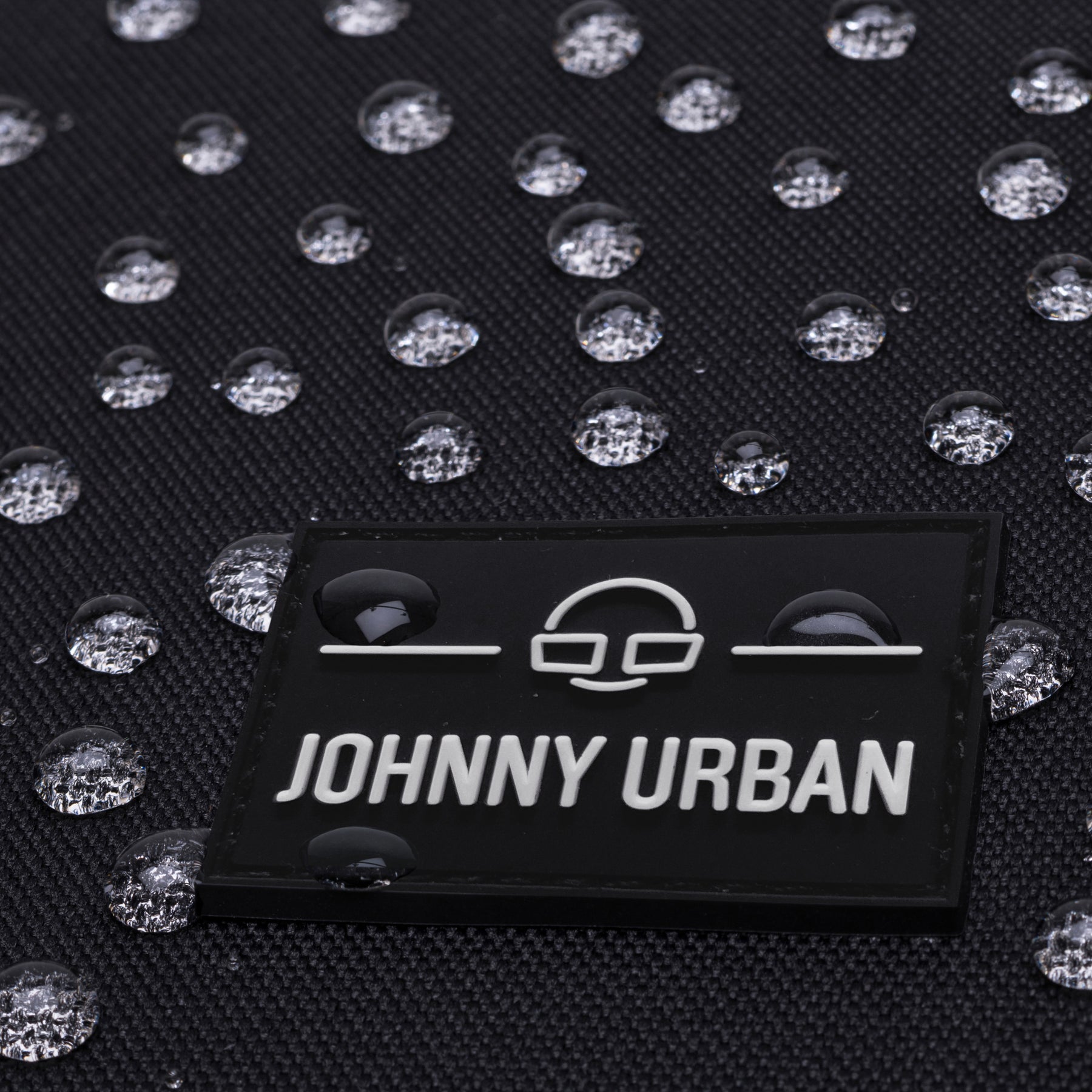 Wasserabweisendes Gewebe mit Johnny Urban Logo-Aufnäher auf schwarzem Rolltop Rucksack Allen Medium
