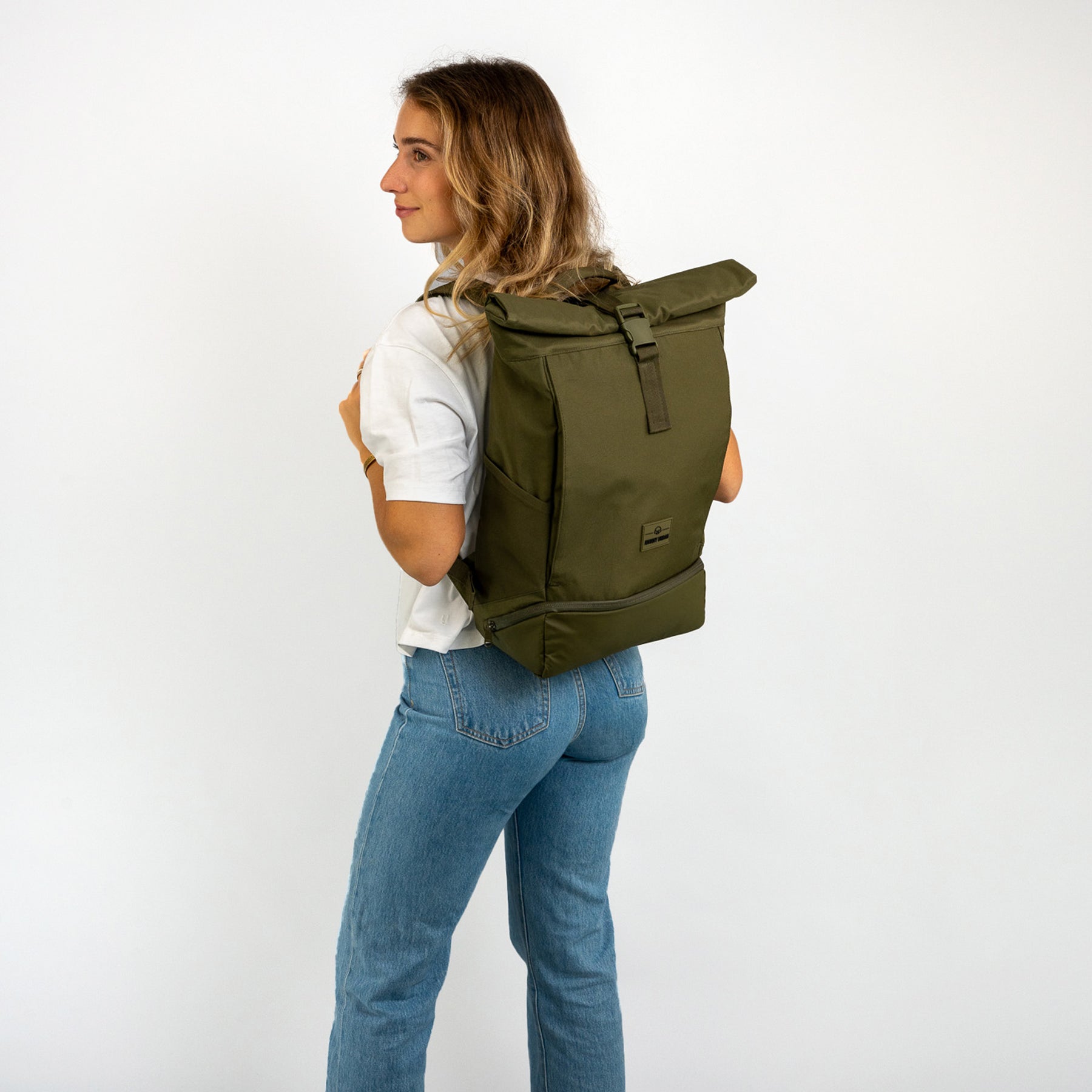 Frau trägt olivgrünen Rolltop Rucksack 'Allen Medium' mit verschlossenem Rollverschluss
