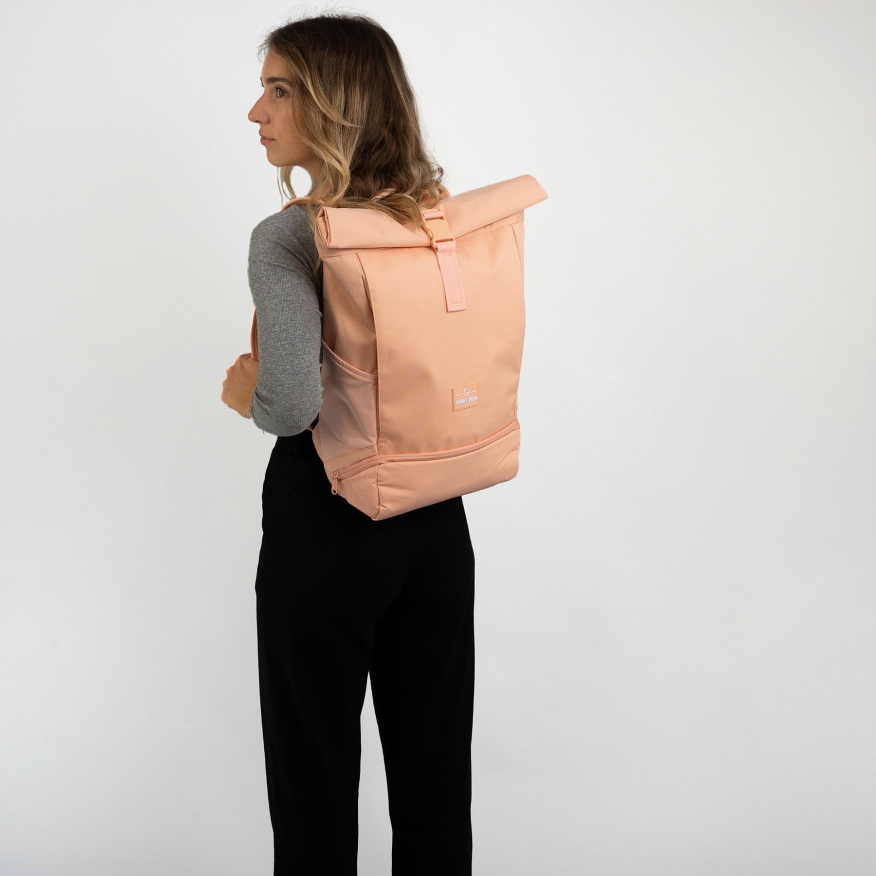 Frau trägt pfirsichfarbenen Rolltop Rucksack 'Allen Medium' von Johnny Urban, seitliche Ansicht
