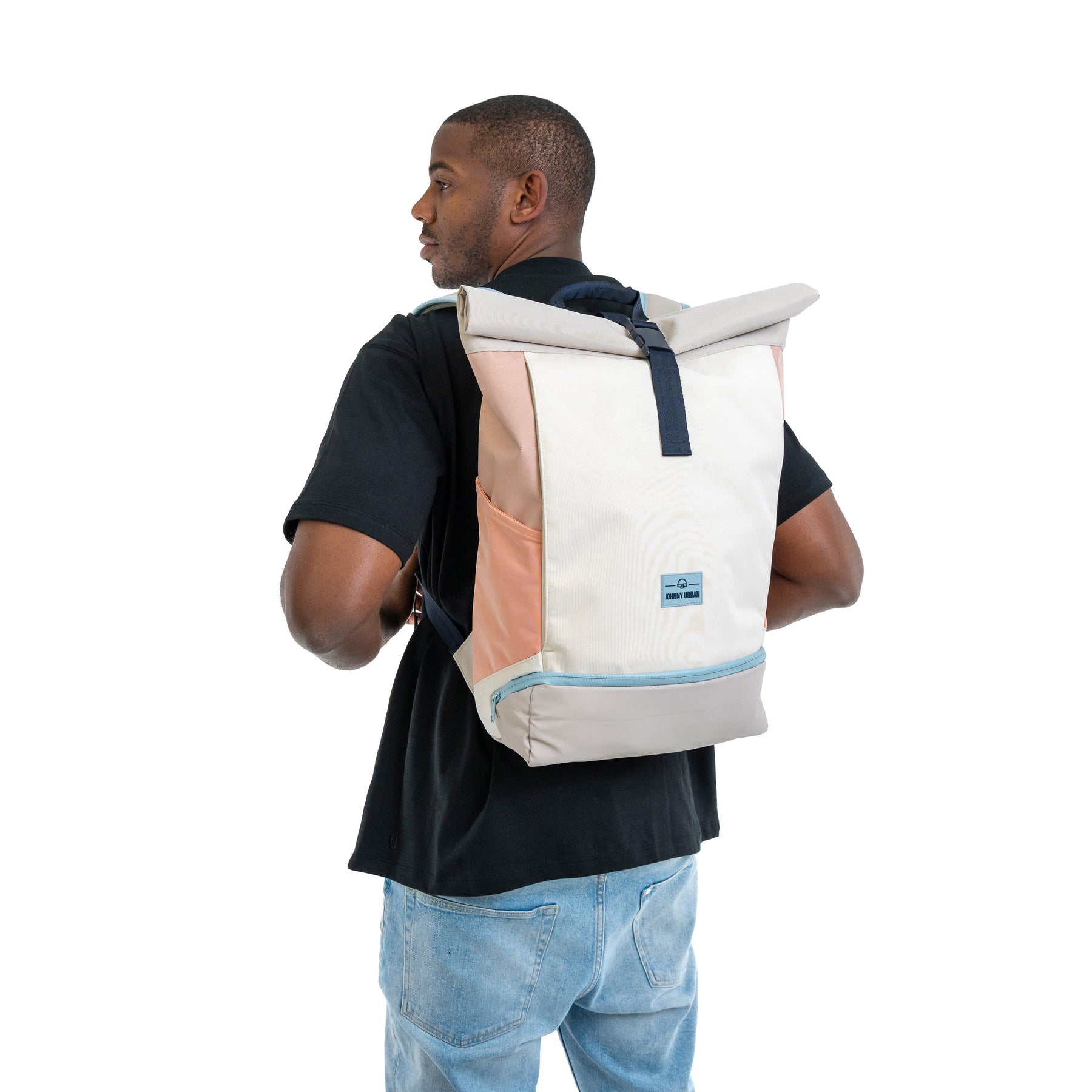 Mann mit Rolltop-Rucksack Allen Large in Sand-Rose von Johnny Urban, schwarzes T-Shirt, blaue Jeans