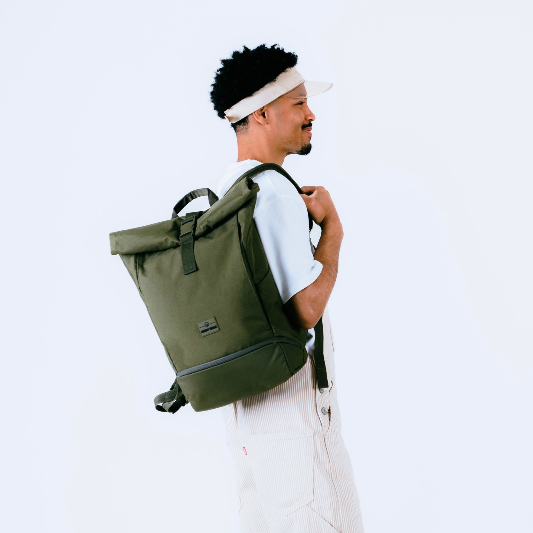 Mann mit olivgrünem Rolltop-Rucksack 'Allen Medium' von Johnny Urban, seitlich stehend