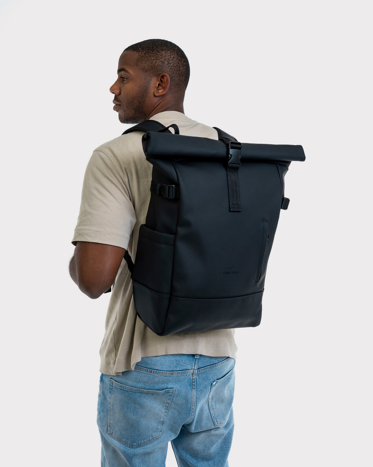 Mann trägt schwarzen Rolltop Rucksack 'Harvey Large' aus robustem Material