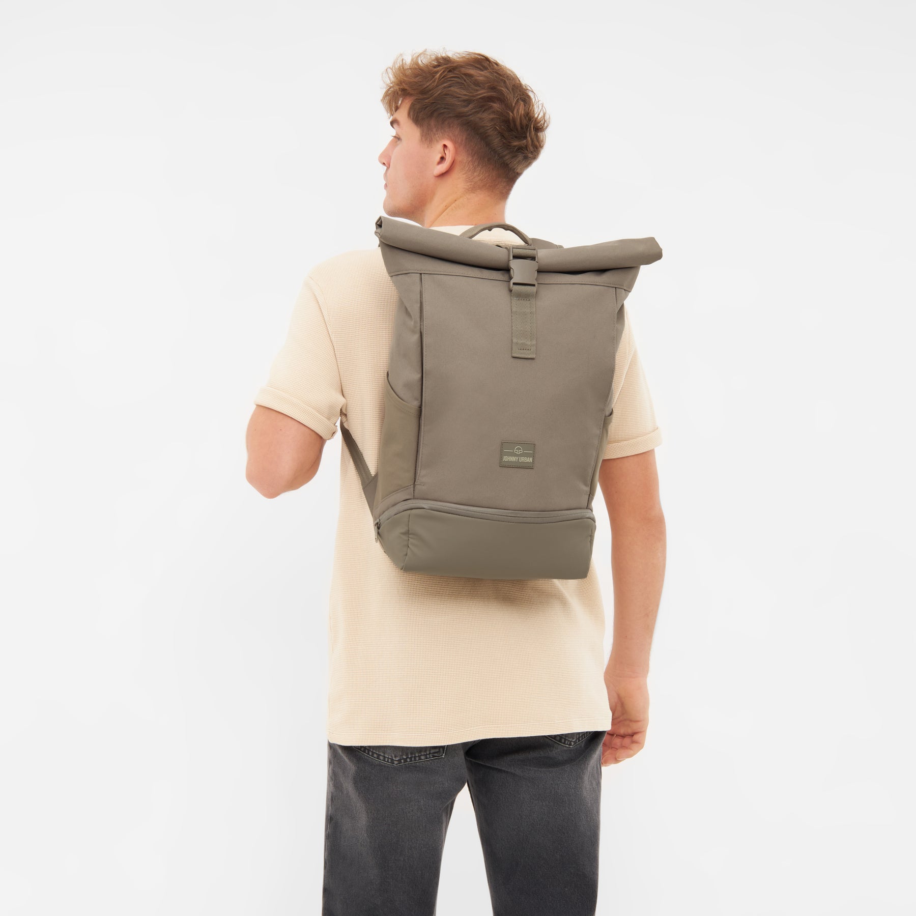 Männliches Modell trägt braunen Johnny Urban Rolltop Rucksack 'Allen Medium' mit Schnallenverschluss