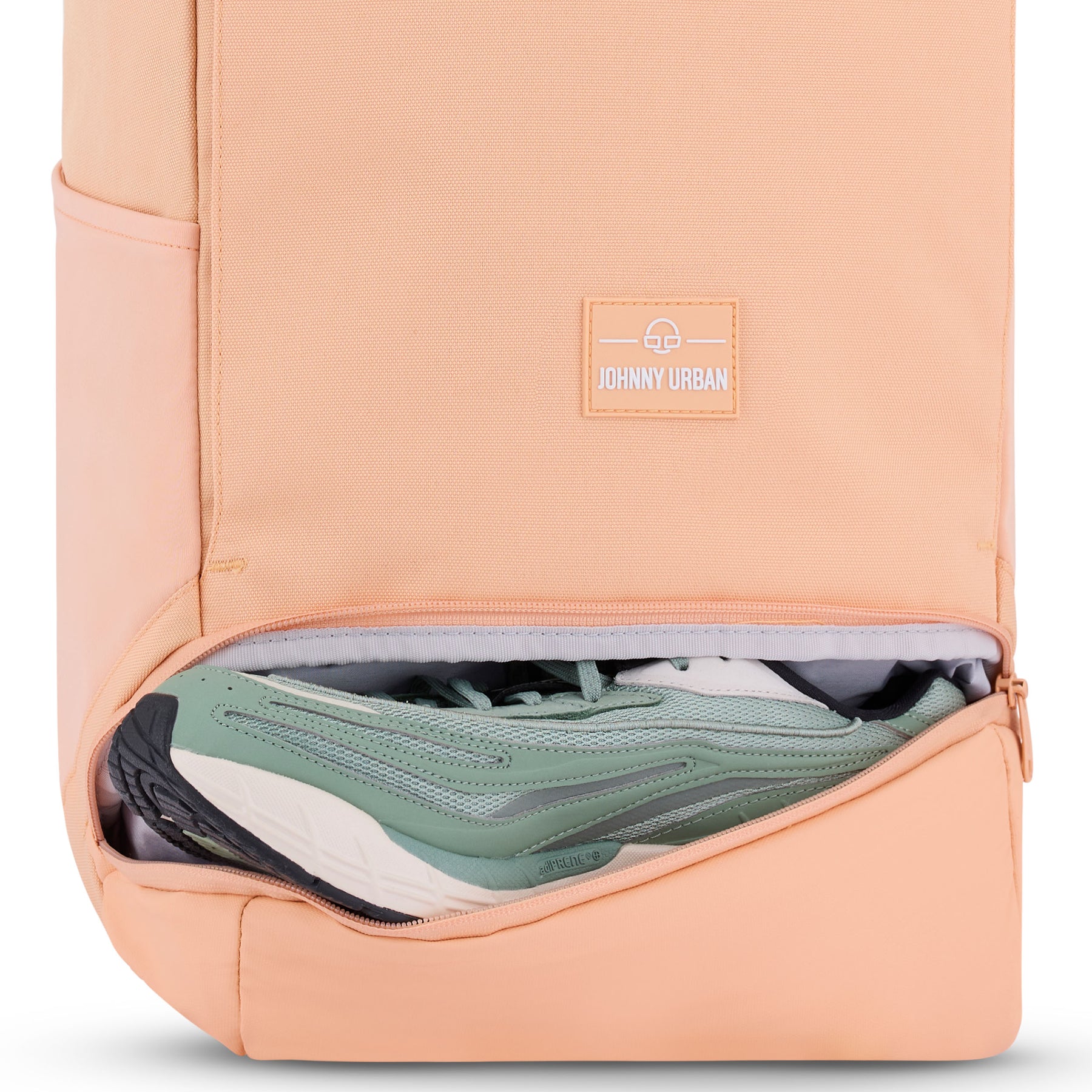 Pfirsichfarbener Rolltop-Rucksack 'Allen Medium' mit geöffnetem Schuhfach und grün-weißen Sneakern