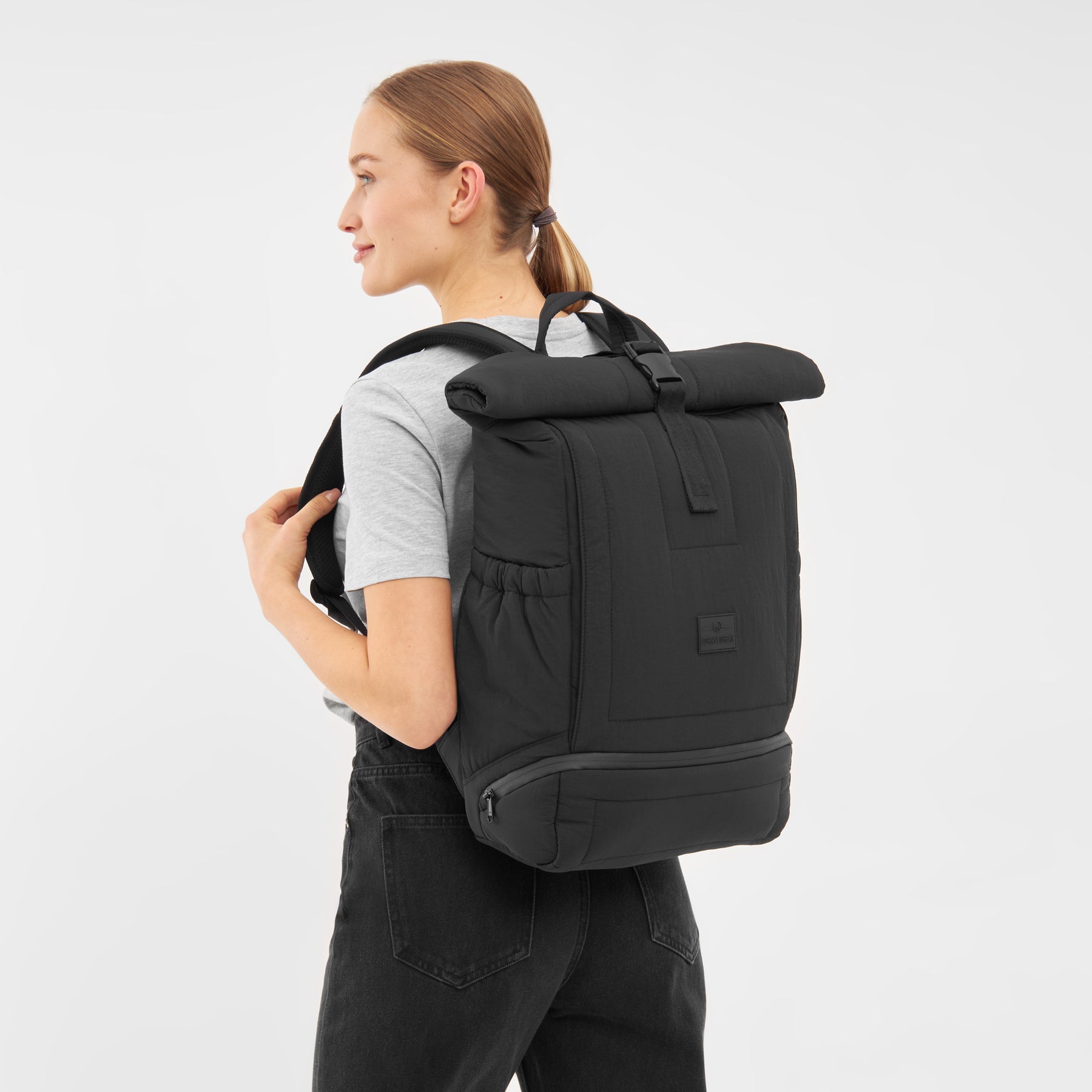 Frau trägt schwarzen gepolsterten Rolltop Rucksack ‚Kyle‘ von Johnny Urban mit seitlichen Taschen