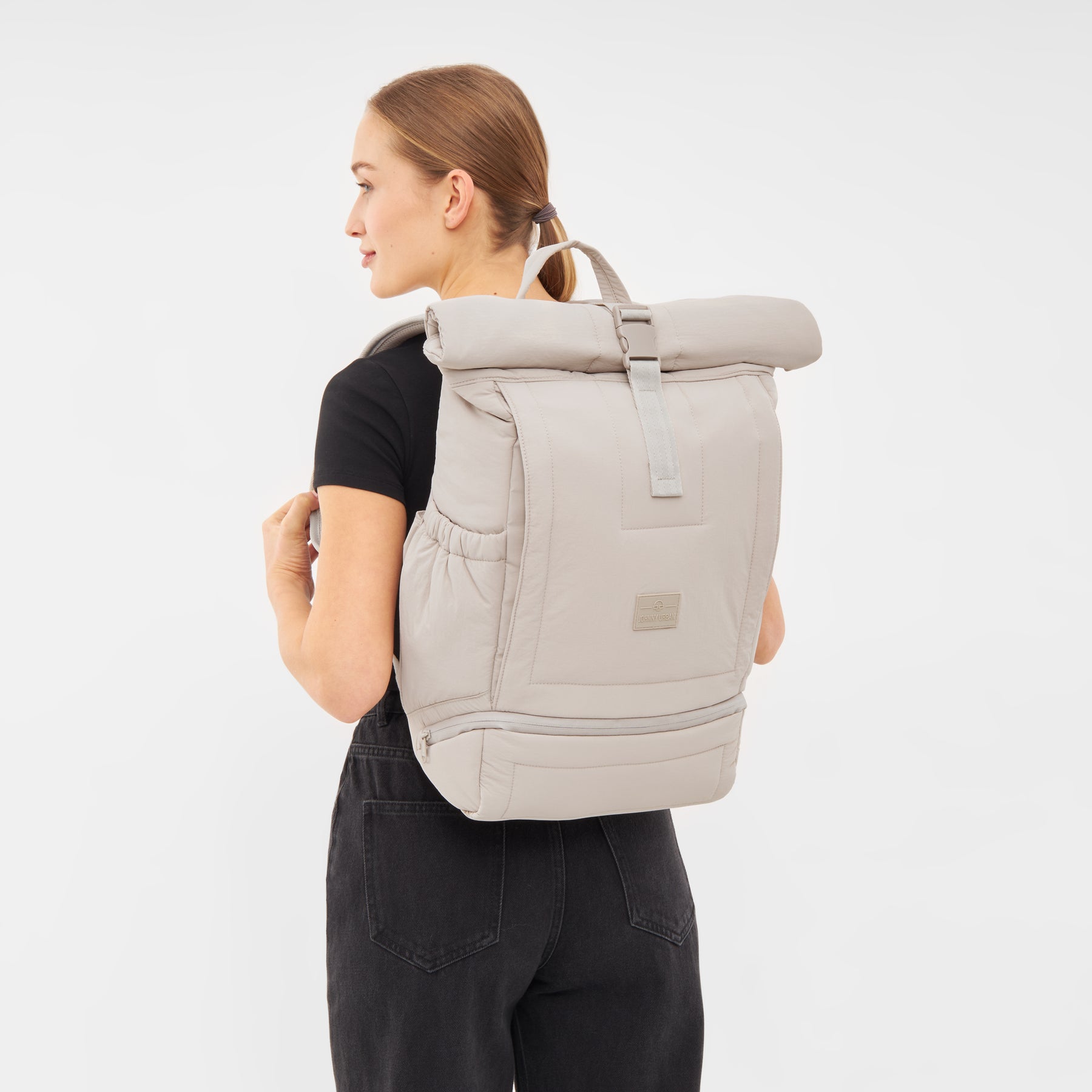 Beiger Rolltop Rucksack 'Kyle' von Johnny Urban an einer Frau mit schwarzem T-Shirt und schwarzer Hose