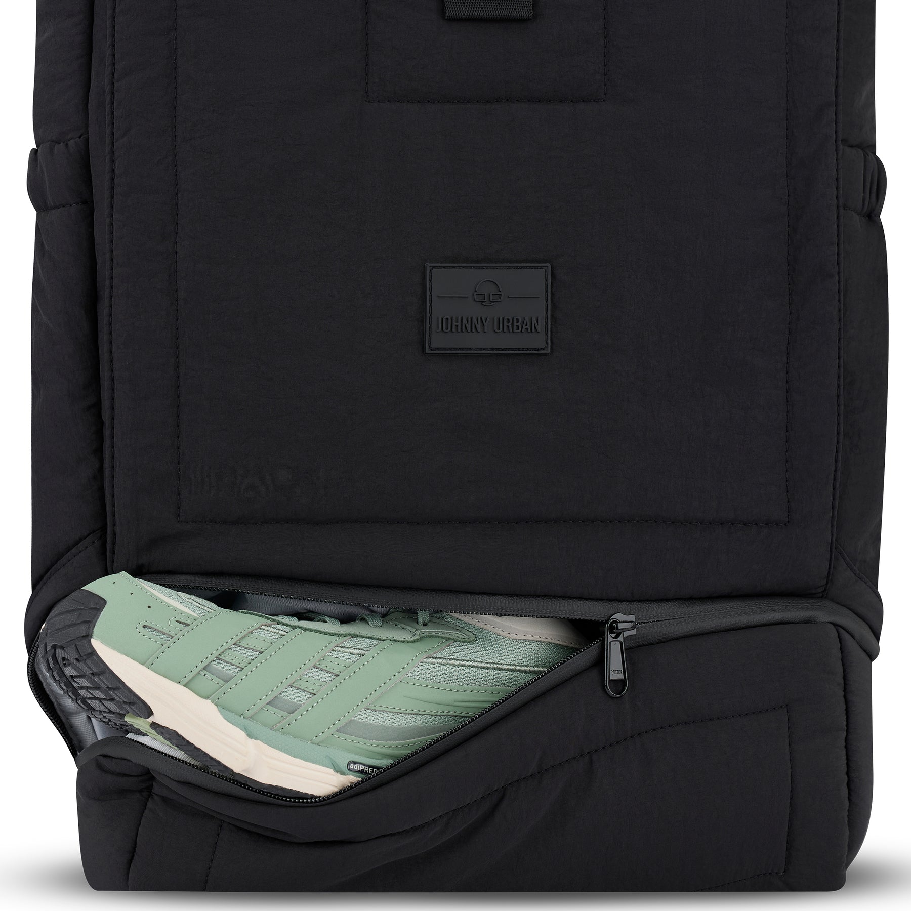 Schwarzer Rolltop Rucksack 'Kyle' von Johnny Urban mit geöffnetem, gepolstertem Schuhfach und grün-weißen Sportschuhen