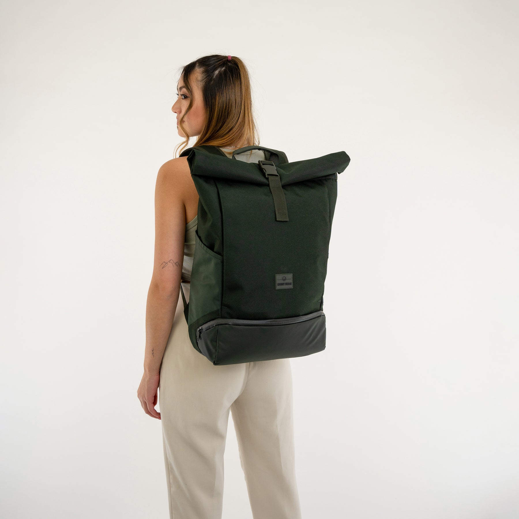 Frau trägt schwarzen Rolltop Rucksack 'Allen Large' von Johnny Urban mit Lederdetails auf hellem Hintergrund