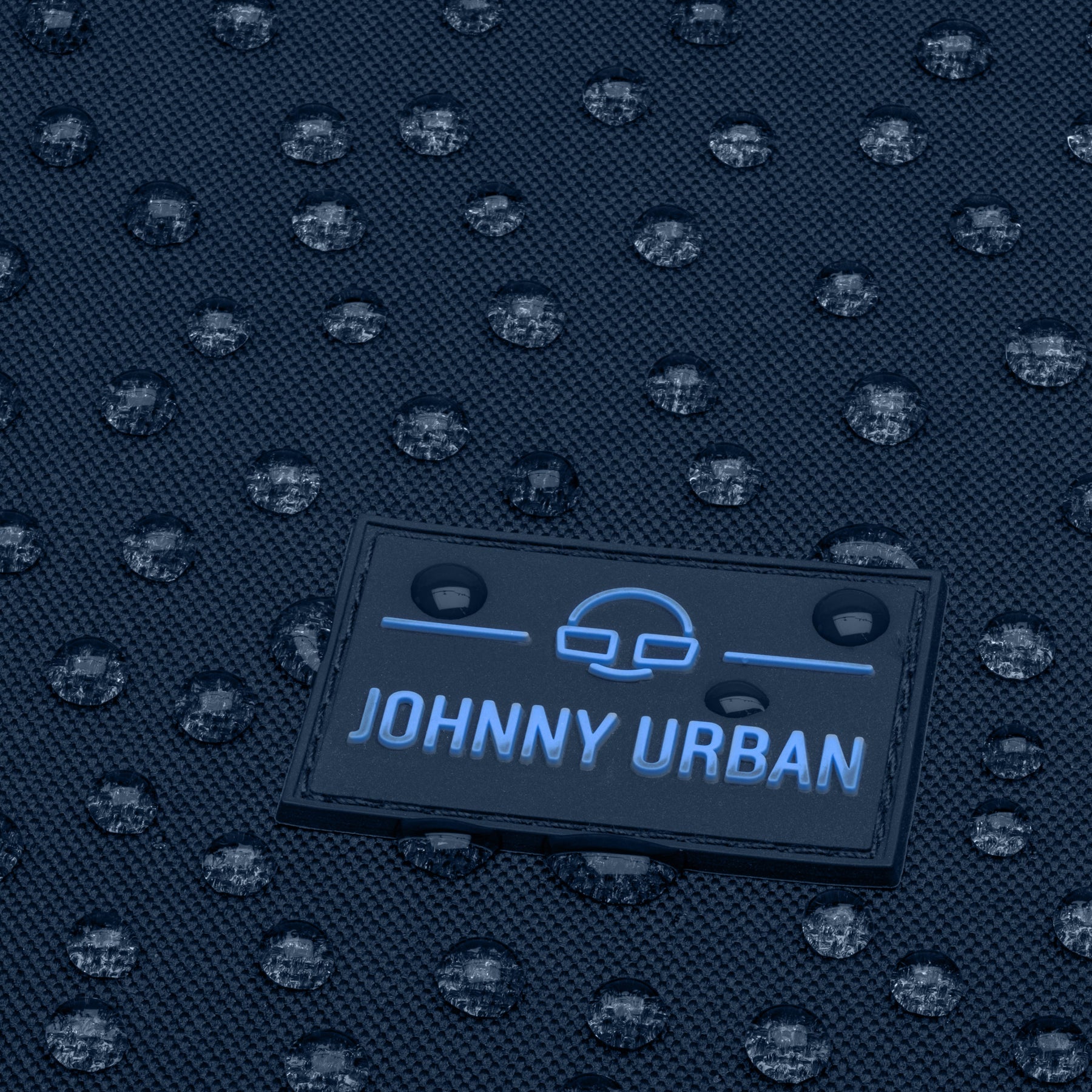 Close-up des wasserfesten blauen Johnny Urban Logos auf dem Rolltop Rucksack Allen Medium