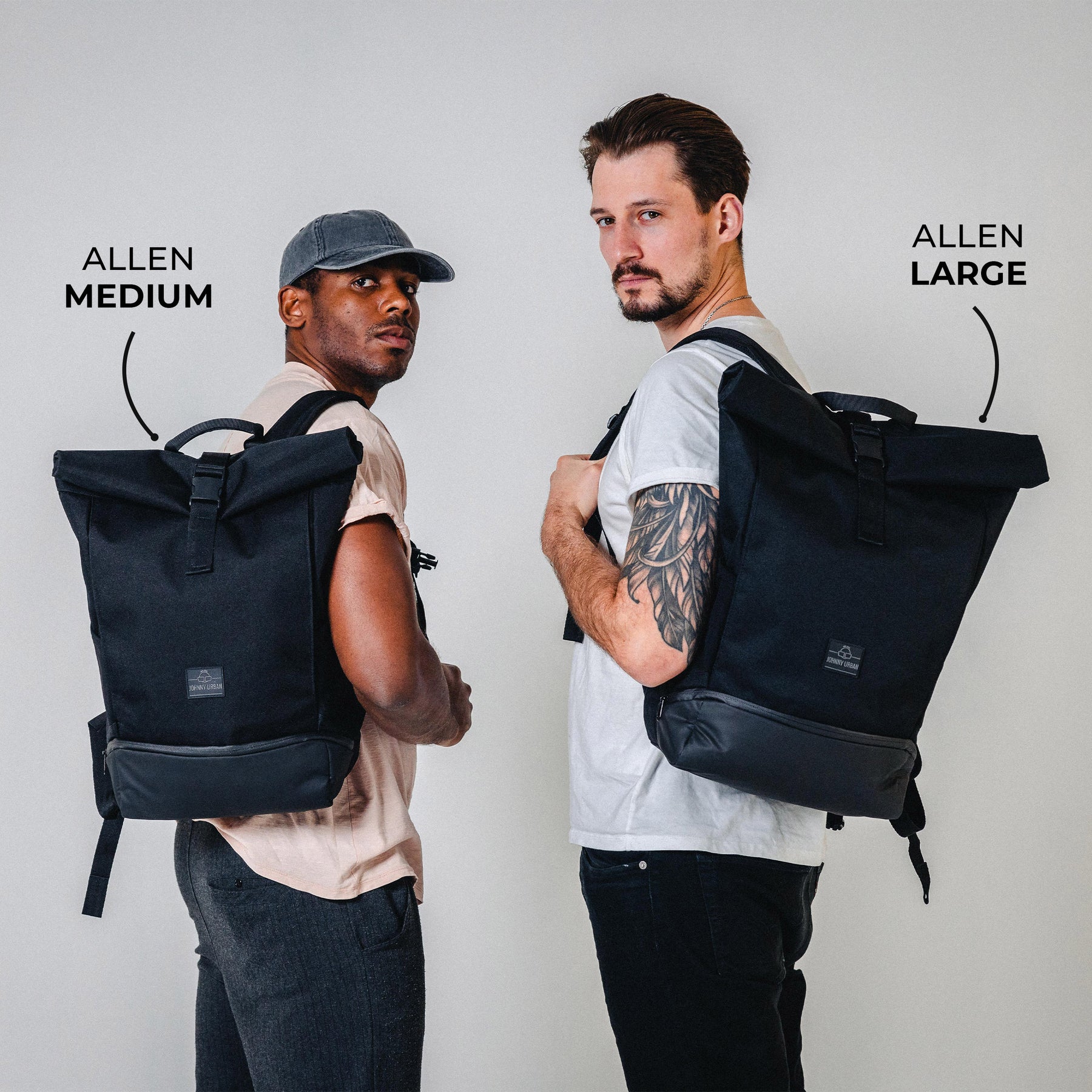 Zwei Männer tragen schwarze Rolltop-Rucksäcke von Johnny Urban, links 'Allen Medium', rechts 'Allen Large'
