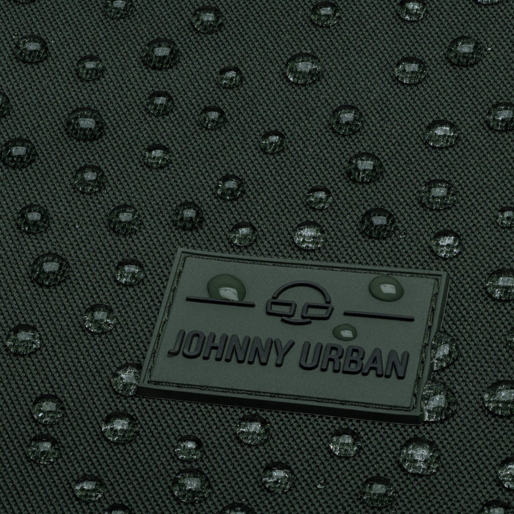 Nahaufnahme eines grünfarbenen wasserabweisenden Johnny Urban Rolltop-Rucksacks mit Wassertropfen