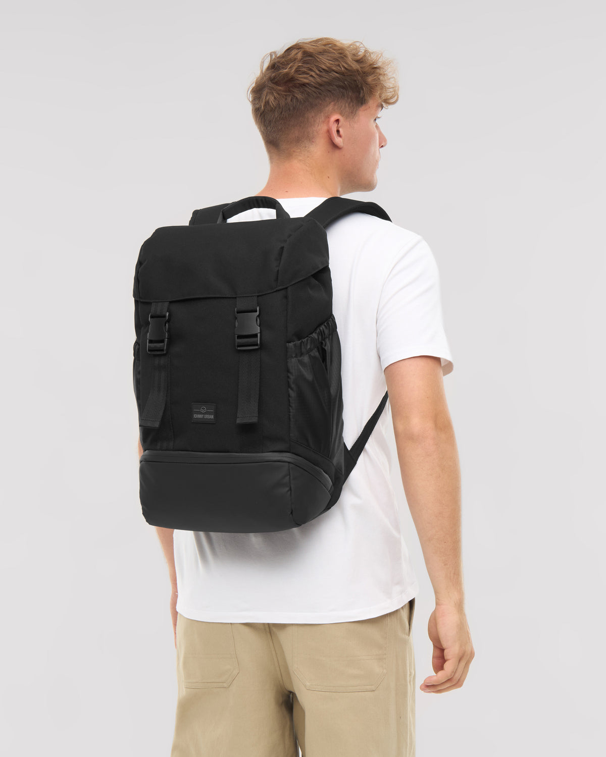 Mann trägt schwarzen Rucksack 'Nico' von Johnny Urban, weiße T-Shirt, beige Hose
