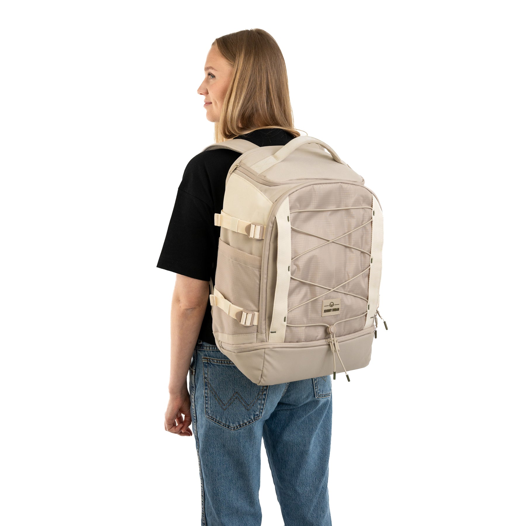Frau trägt beigen Johnny Urban Rucksack 'Jack' mit verstellbaren Gurten und elastischem Netzt auf der Vorderseite