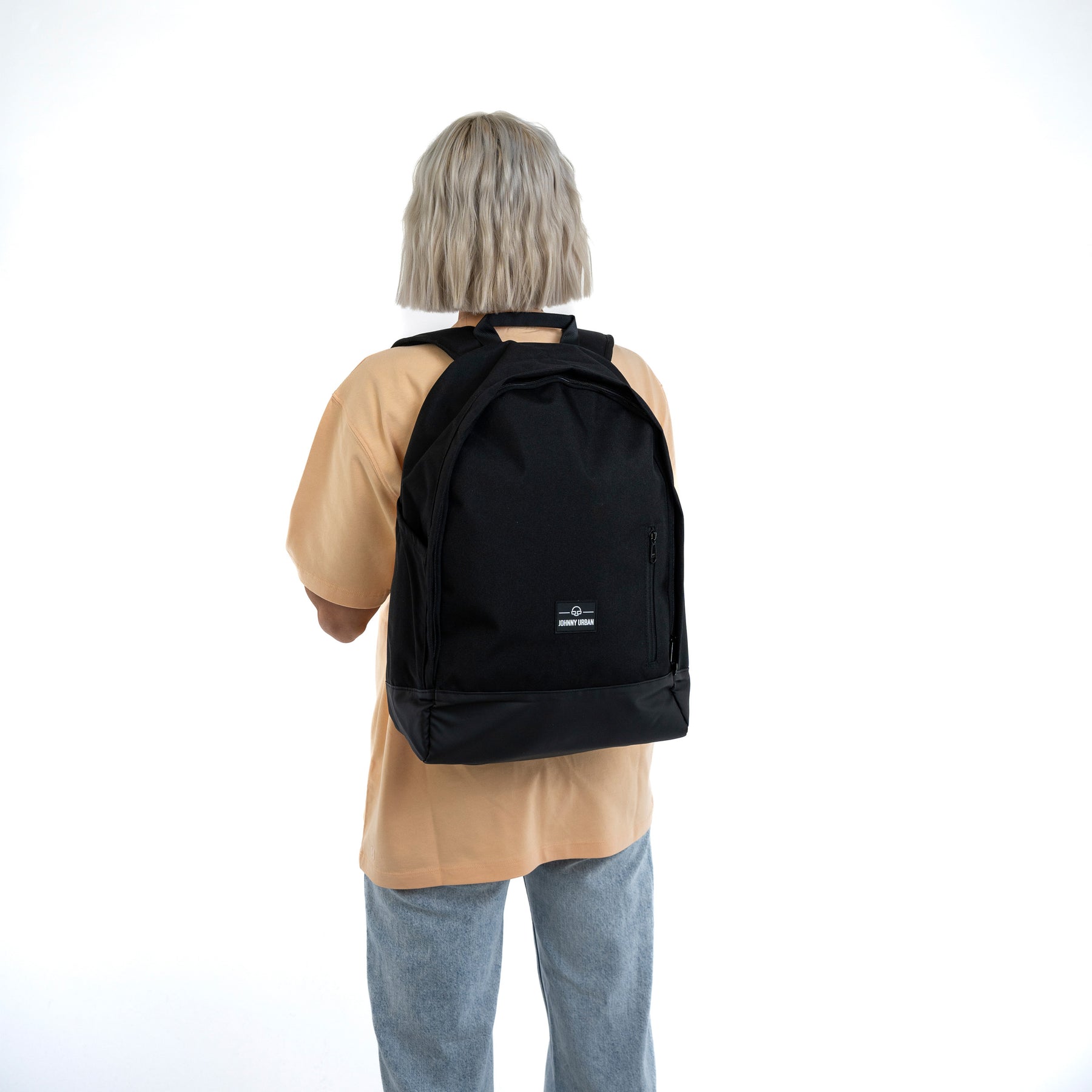 Jugendliche mit schwarzem Johnny Urban Rucksack 'Neo' von hinten, trägt beige T-Shirt und blaue Jeans