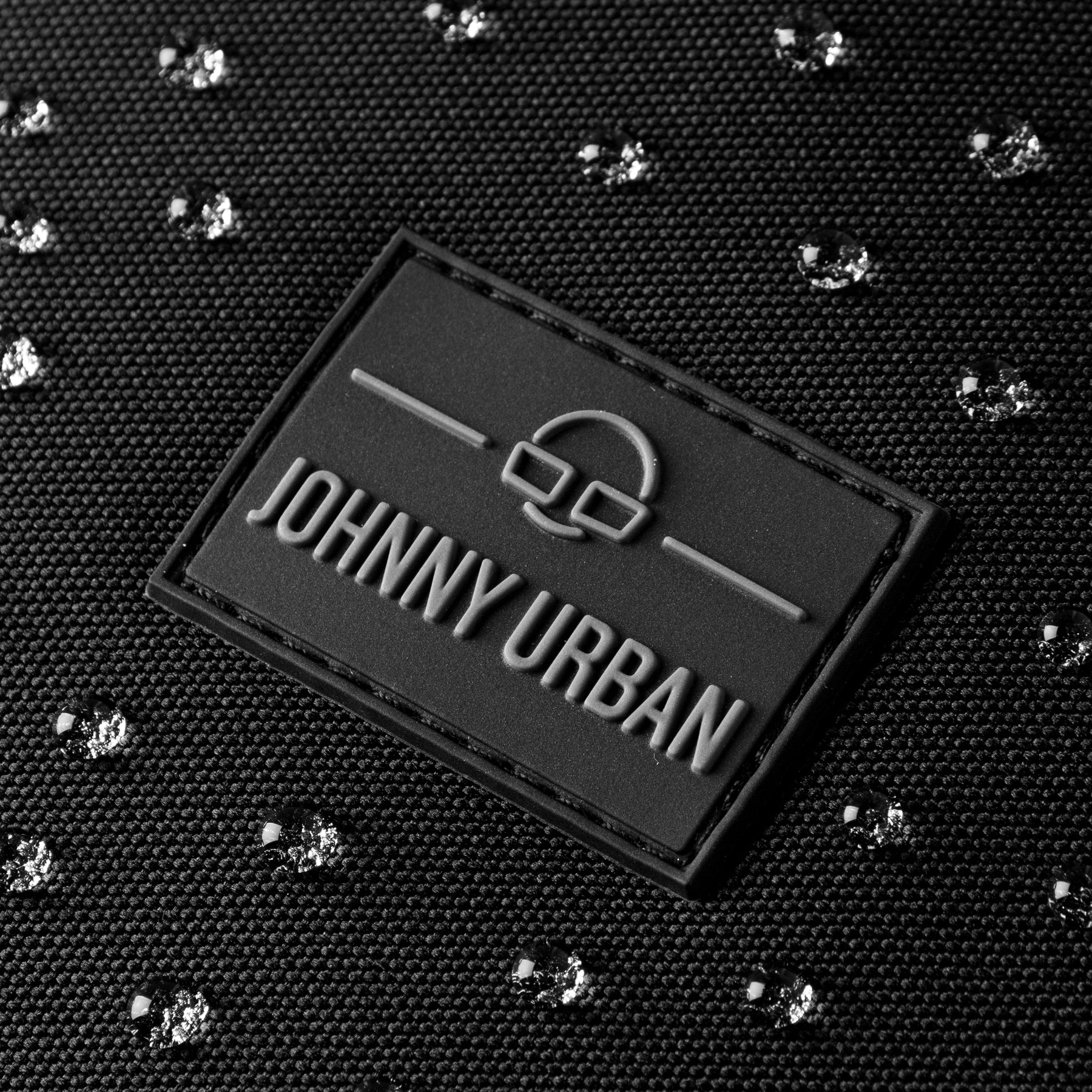 Schwarze Johnny Urban Markierung auf wasserfestem Rucksackgewebe mit Wassertropfen