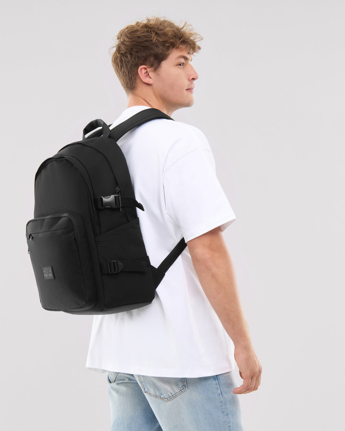 Mann trägt schwarzen Rucksack 'Lian' mit Fronttasche und Schnallen, weiße T-Shirt, blaue Jeans