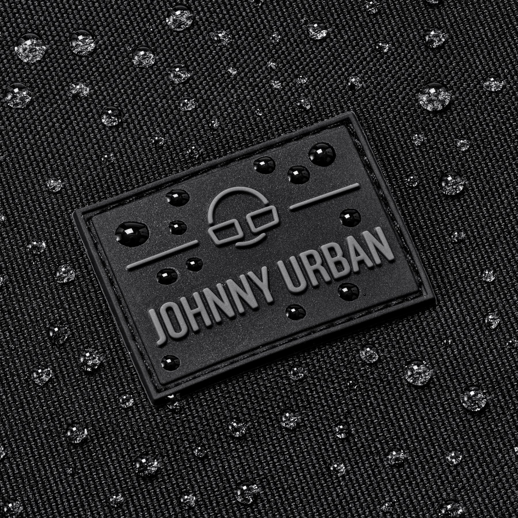 Schwarzes wasserabweisendes Gewebe mit Johnny Urban Logo und Wassertropfen