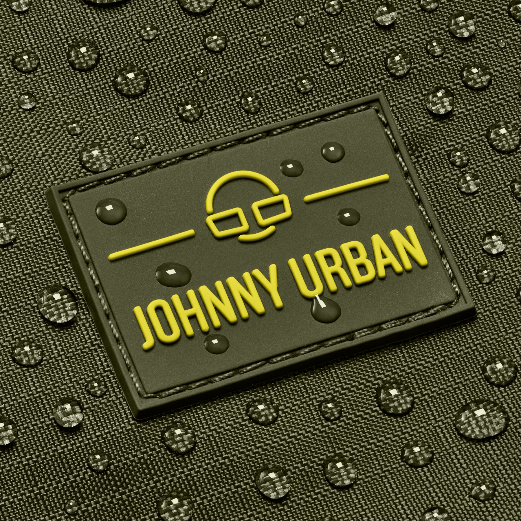 Nahaufnahme des Johnny Urban Logos auf einer olivfarbenen Duffle Bag "Shawn Medium" mit Wassertropfen