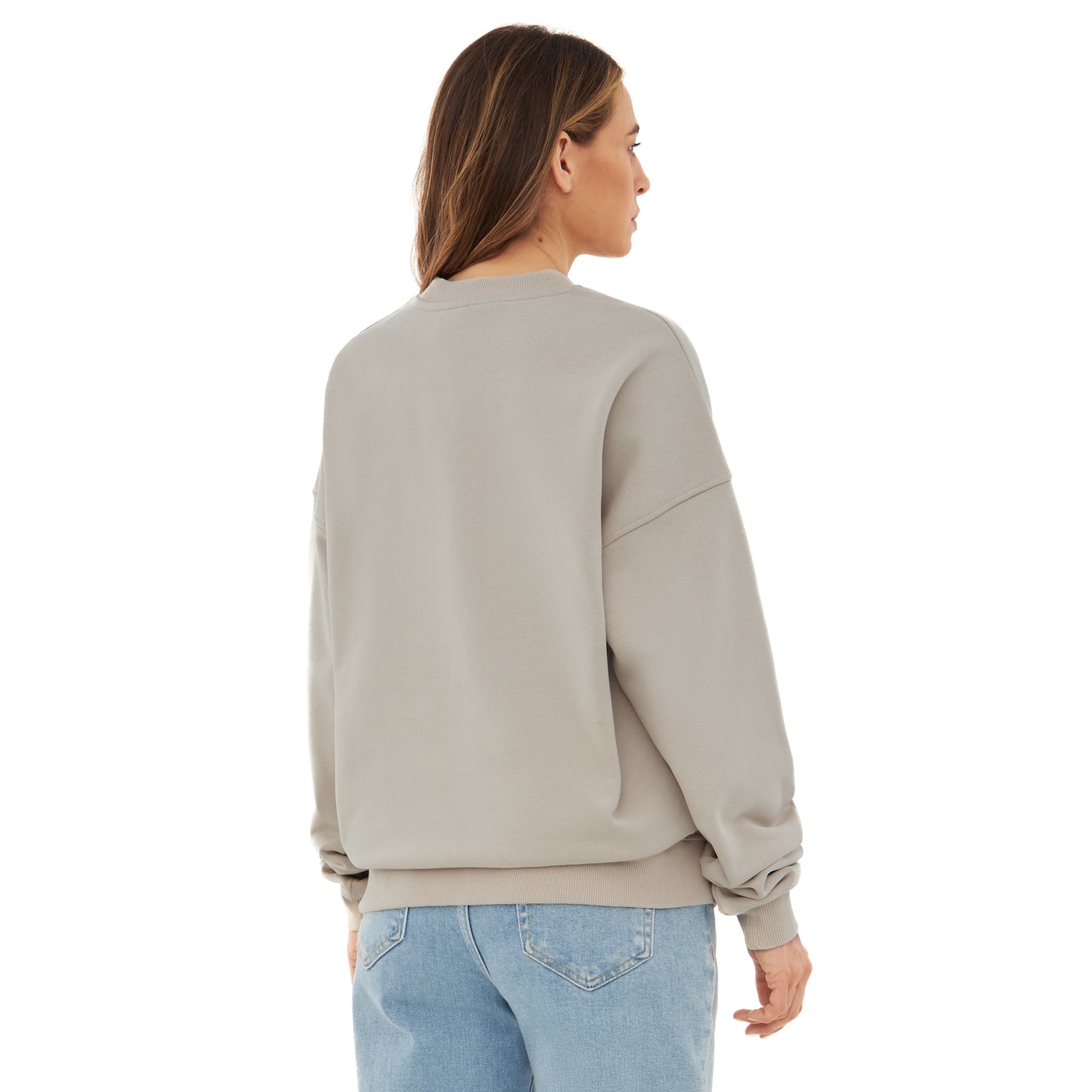 Damen trägt oversized Crewneck 'Carter' Pullover in Beige von hinten mit hellblauen Jeans